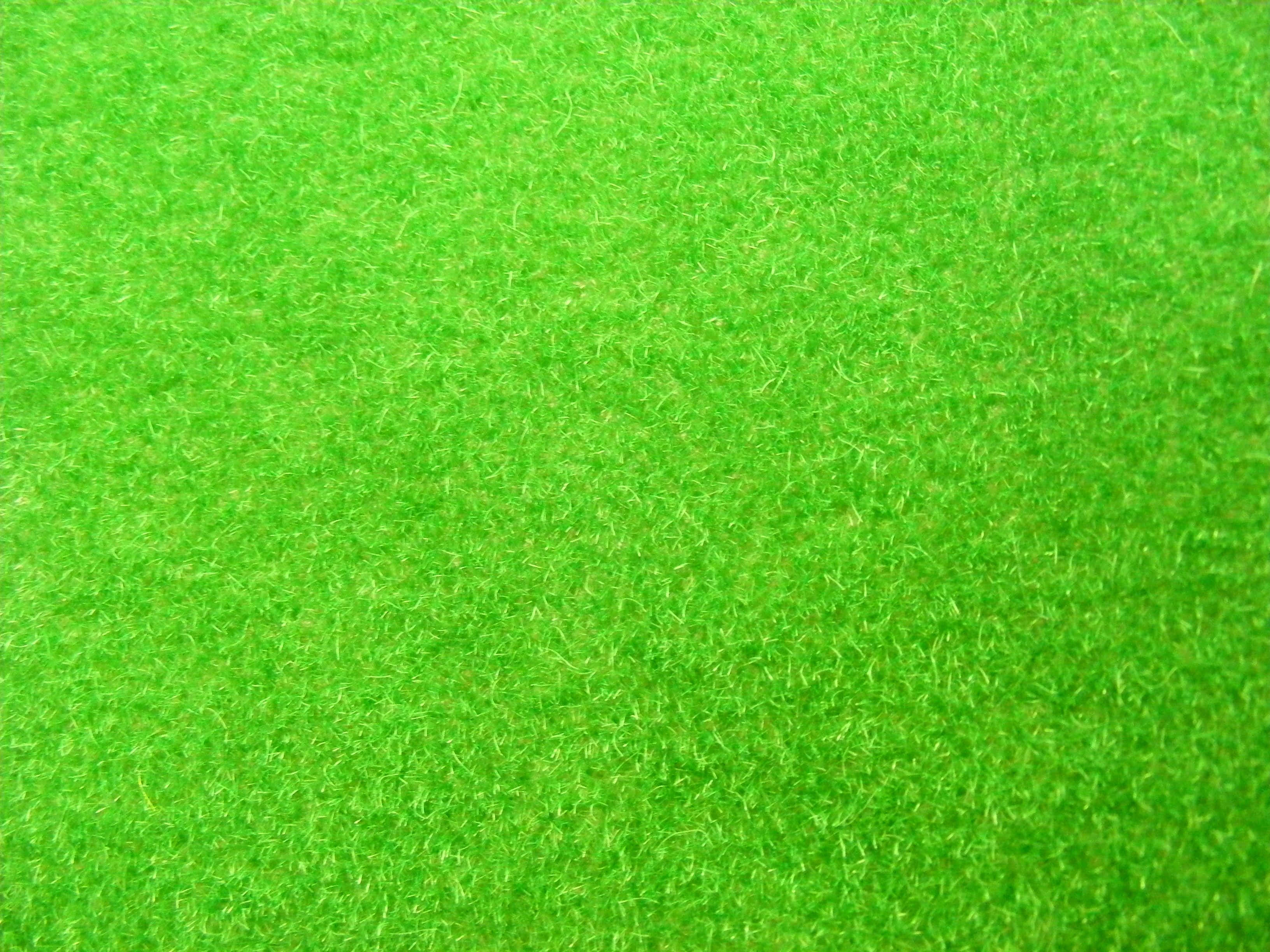 Green Grass 桌布 壁紙 — 充滿活力的綠色人造草皮，帶有細膩紋理的纖維覆蓋整個畫面。