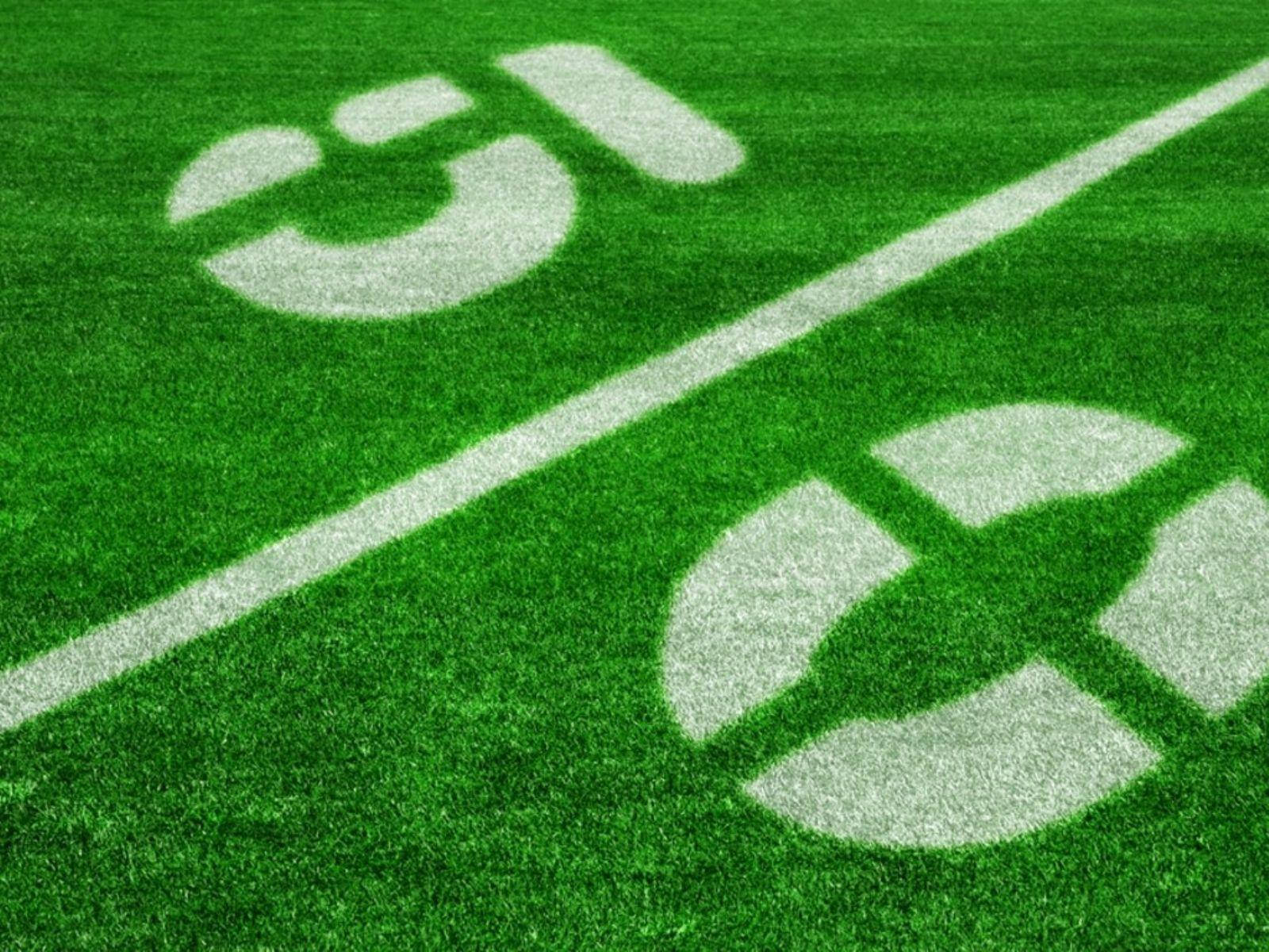 酷炫足球 桌布 壁紙 — 充滿活力的綠色人造草皮特寫，帶有清晰的白色碼線和端區標記。