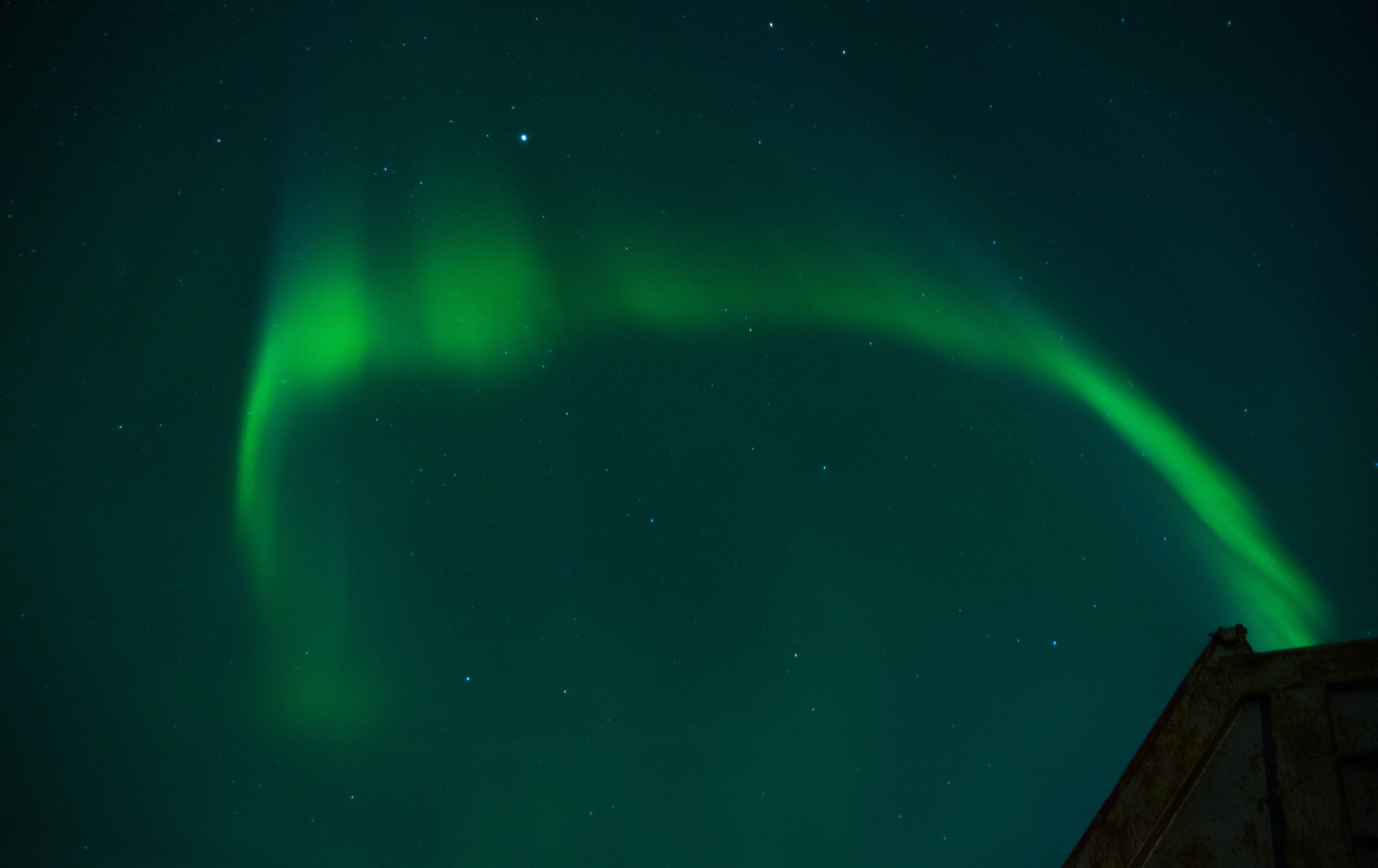 Beautiful Night 桌布 壁紙 — 充滿活力的綠色北極光在星空下，在風化的建築屋頂上舞動。