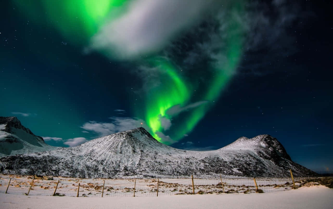aurora borealis 桌布 壁紙 — 充滿活力的綠色北極光在星空冬夜下，在積雪的山峰上舞動。