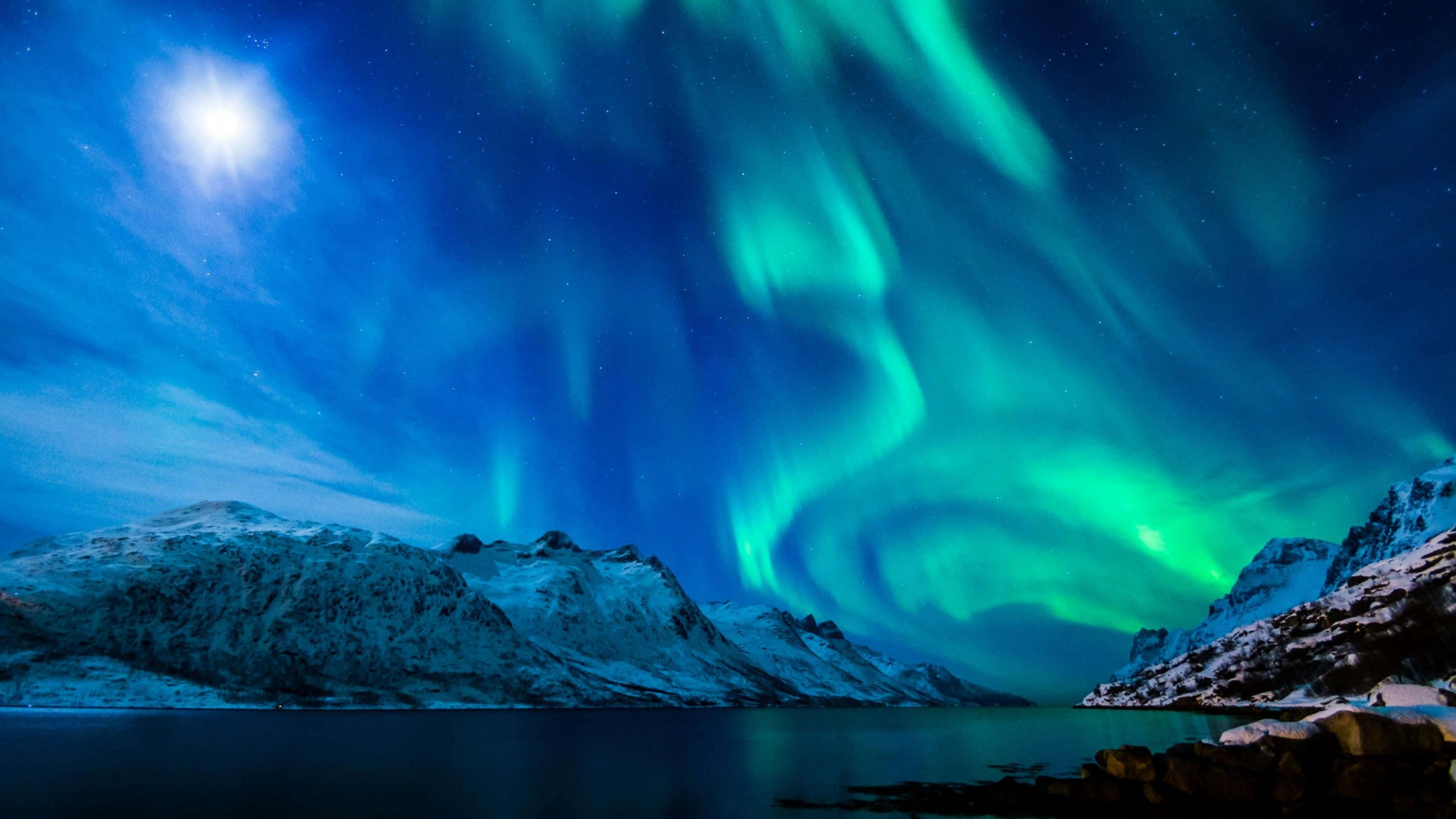 Aurora 桌布 壁紙 — 充滿活力的綠色北極光在星空夜空中舞動，照耀著白雪覆蓋的山脈和寧靜的反射湖。
