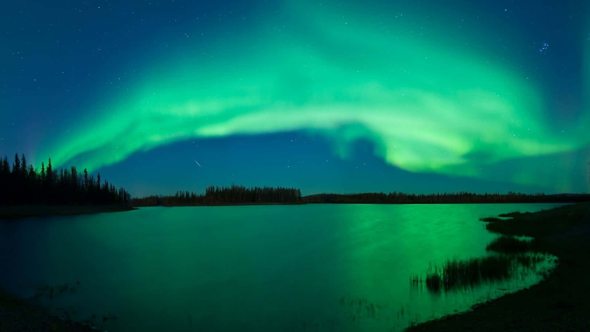 1920x1080 桌布 壁紙 — 充滿活力的綠色北極光在繁星點點的夜空中舞動，平靜的湖面反射出其空靈的光芒。