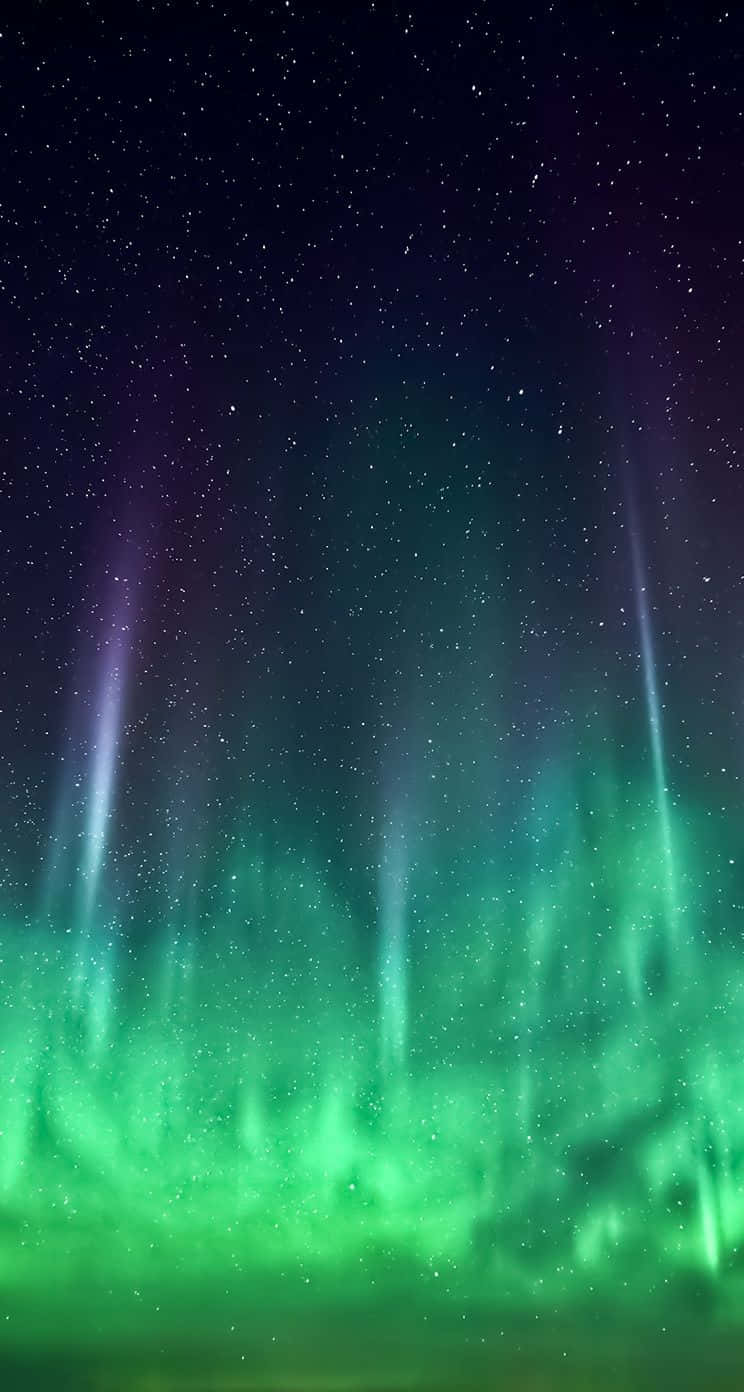iOS 桌布 壁紙 — 充滿活力的綠色和紫色極光在繁星點點的夜空中舞動，垂直的光束照亮了黑暗。