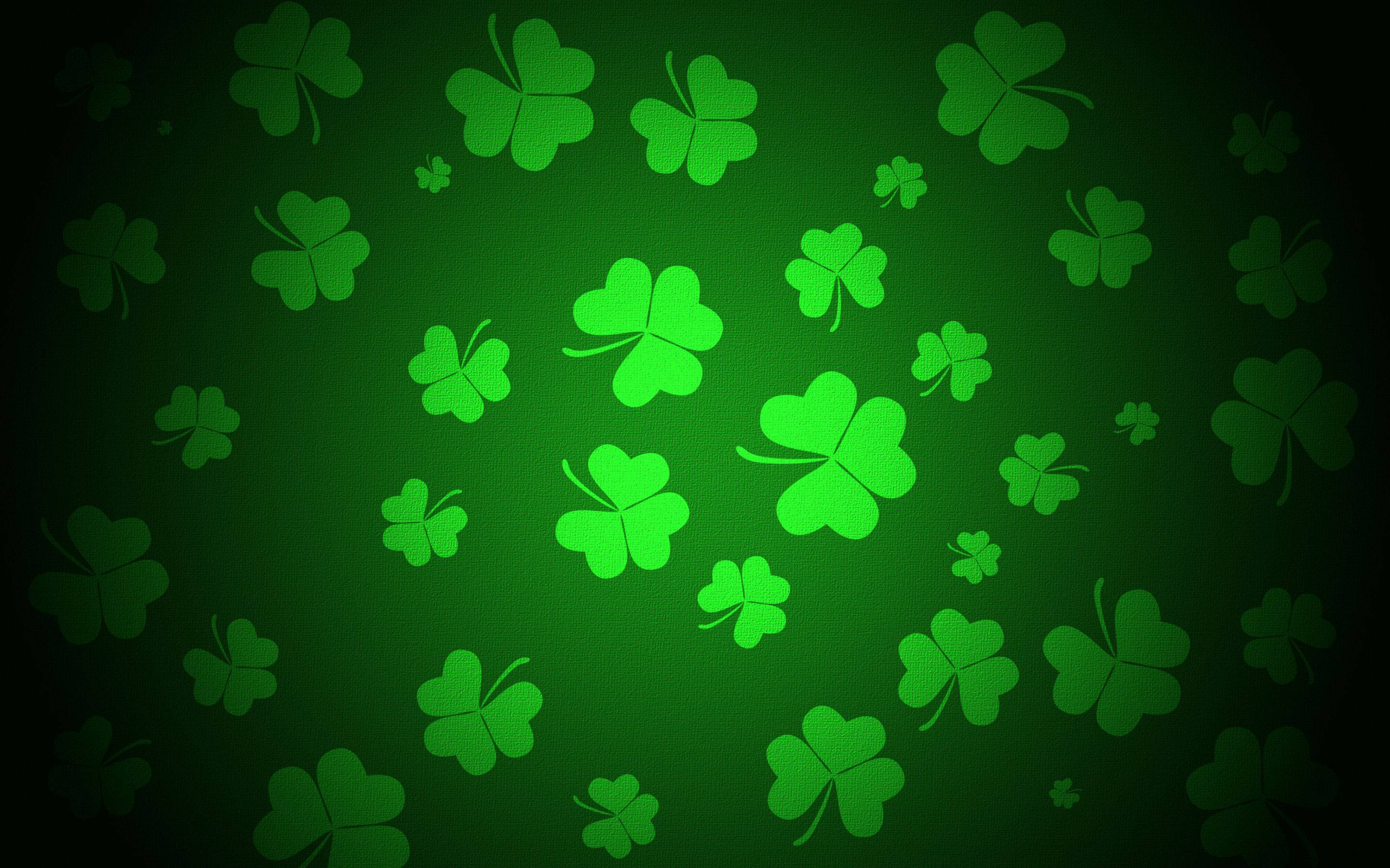 St Patrick's Day 桌布 壁紙 — 充滿活力的綠色四葉草漂浮在帶有微妙紋理的漸變深綠色背景上。