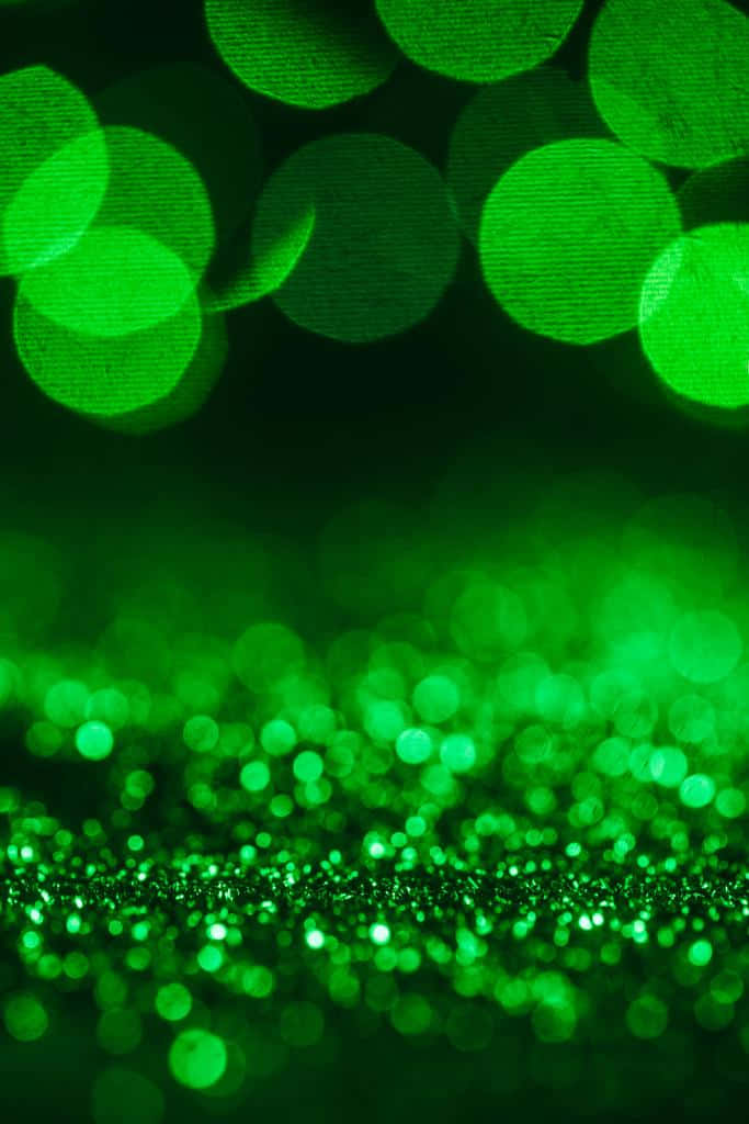 Bokeh 桌布 壁紙 — 充滿活力的綠色散景燈光在黑暗背景下閃爍，並帶有閃閃發光的前景粒子。