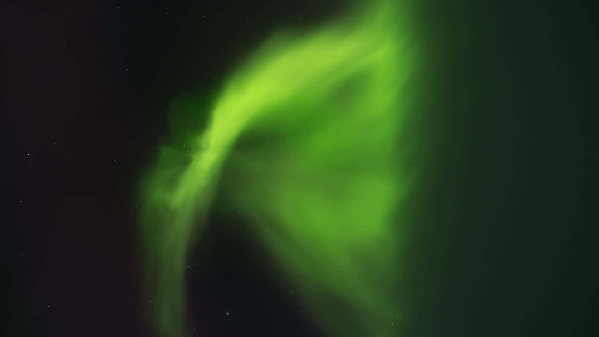 極光 桌布 壁紙 — 充滿活力的綠色極光在繁星點點的夜空中舞動，帶有柔和發光的卷鬚。
