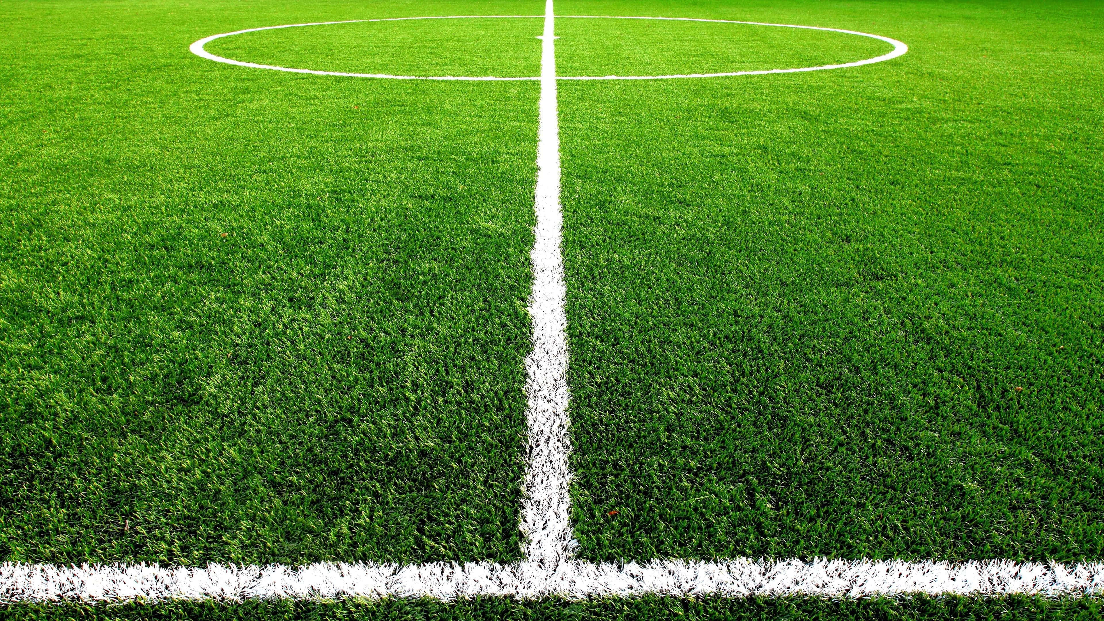 Football Field 桌布 壁紙 — 充滿活力的綠色足球場特寫，帶有清晰白色中圈和分界線。