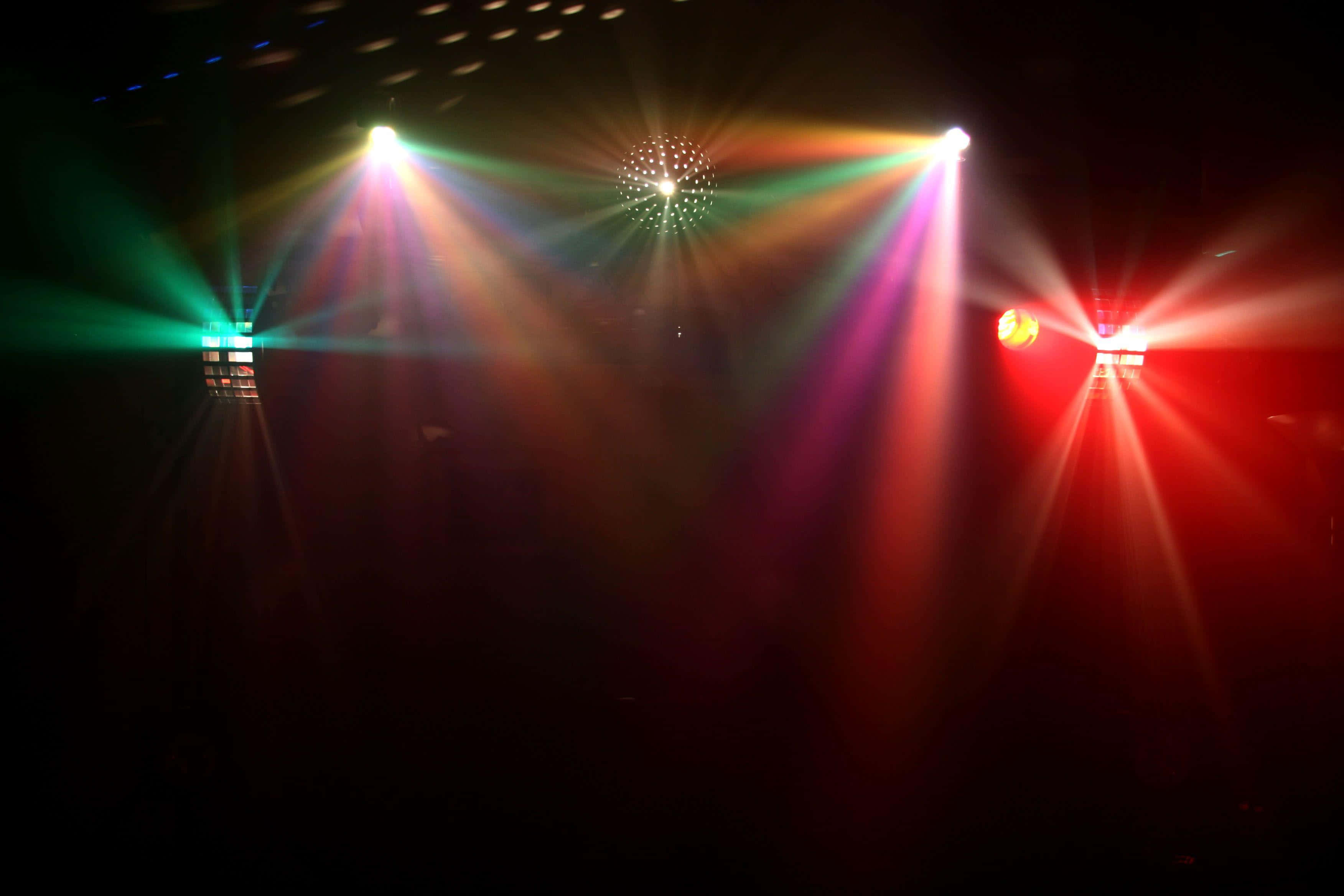 lights 桌布 壁紙 — 充滿活力的舞台燈光以鮮豔的紅色、綠色和白色光線照射在黑暗的音樂會場地，營造出充滿活力的氛圍。