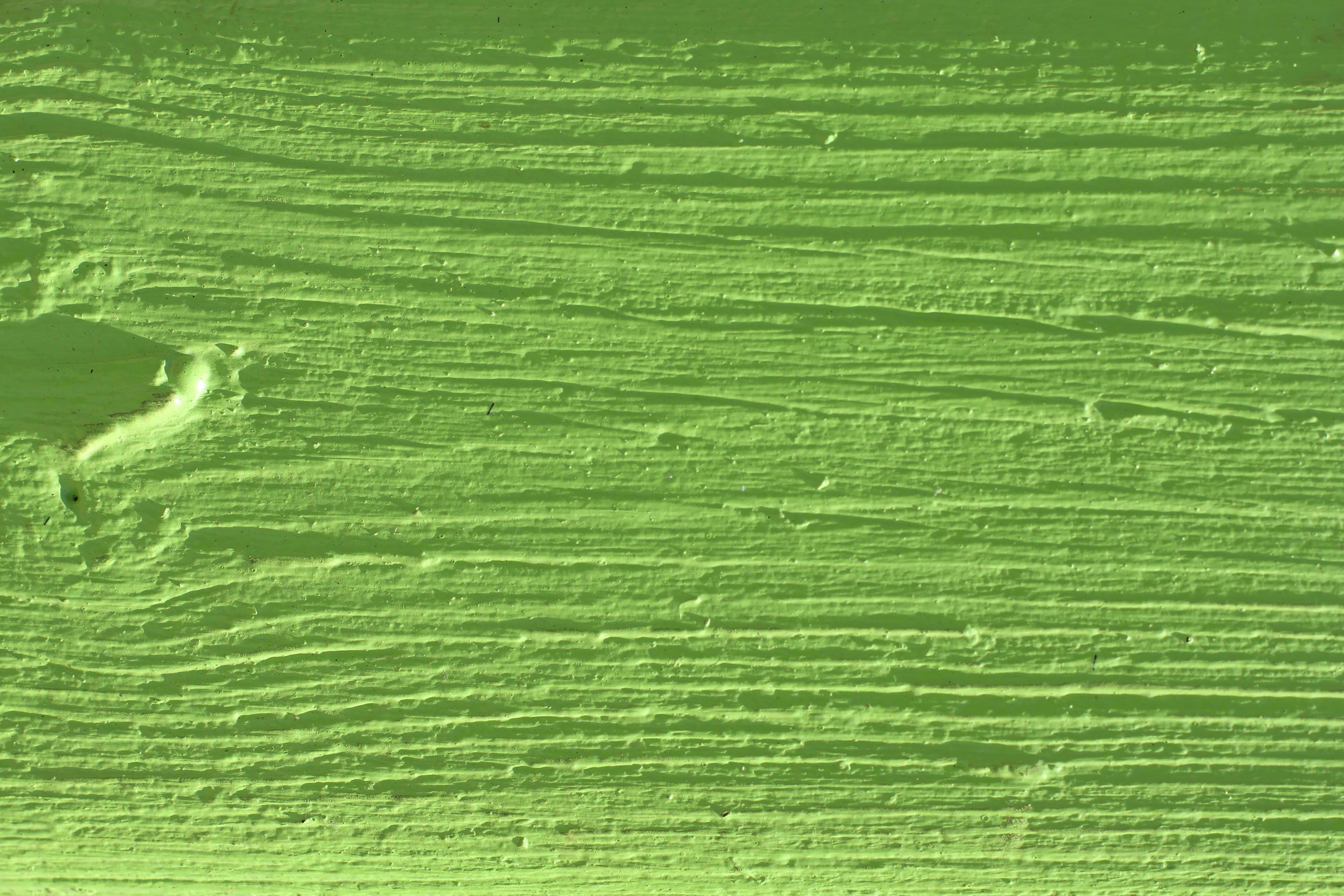 Green Texture 桌布 壁紙 — 充滿活力的萊姆綠色油漆筆觸特寫，展現出紋理豐富的筆觸和下方細微的木紋。