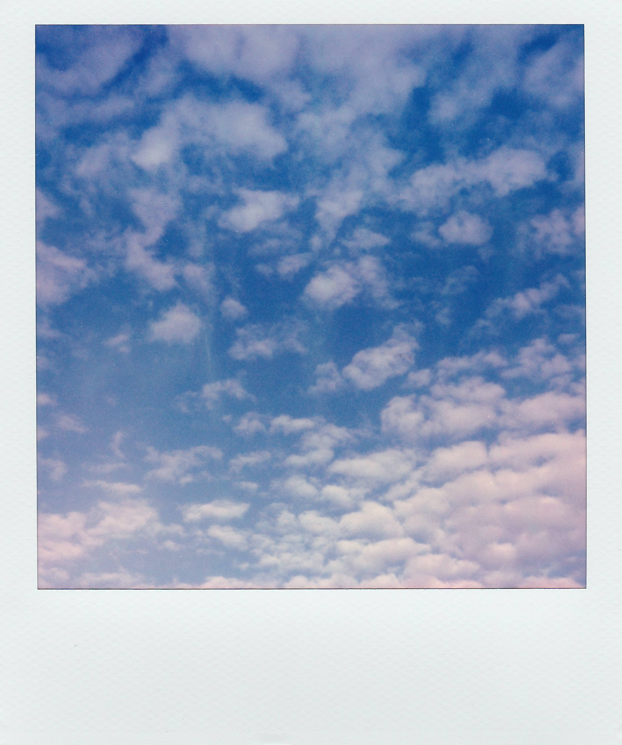 Aesthetic Clouds 桌布 壁紙 — 充滿活力的藍天，佈滿柔軟如棉的雲朵，靠近地平線處帶有粉紅色調。