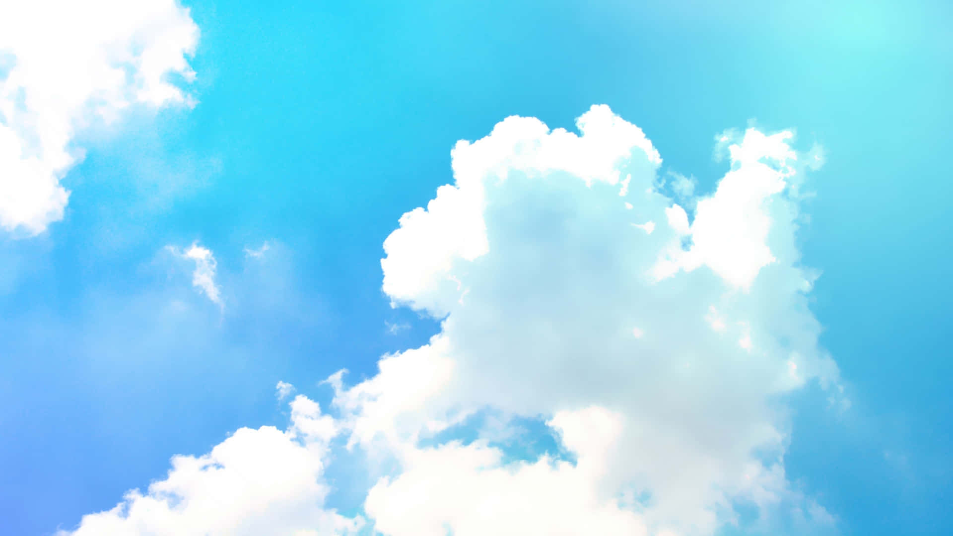 Blue Sky 桌布 壁紙 — 充滿活力的藍天，佈滿蓬鬆的白雲，沐浴在明亮的陽光下。