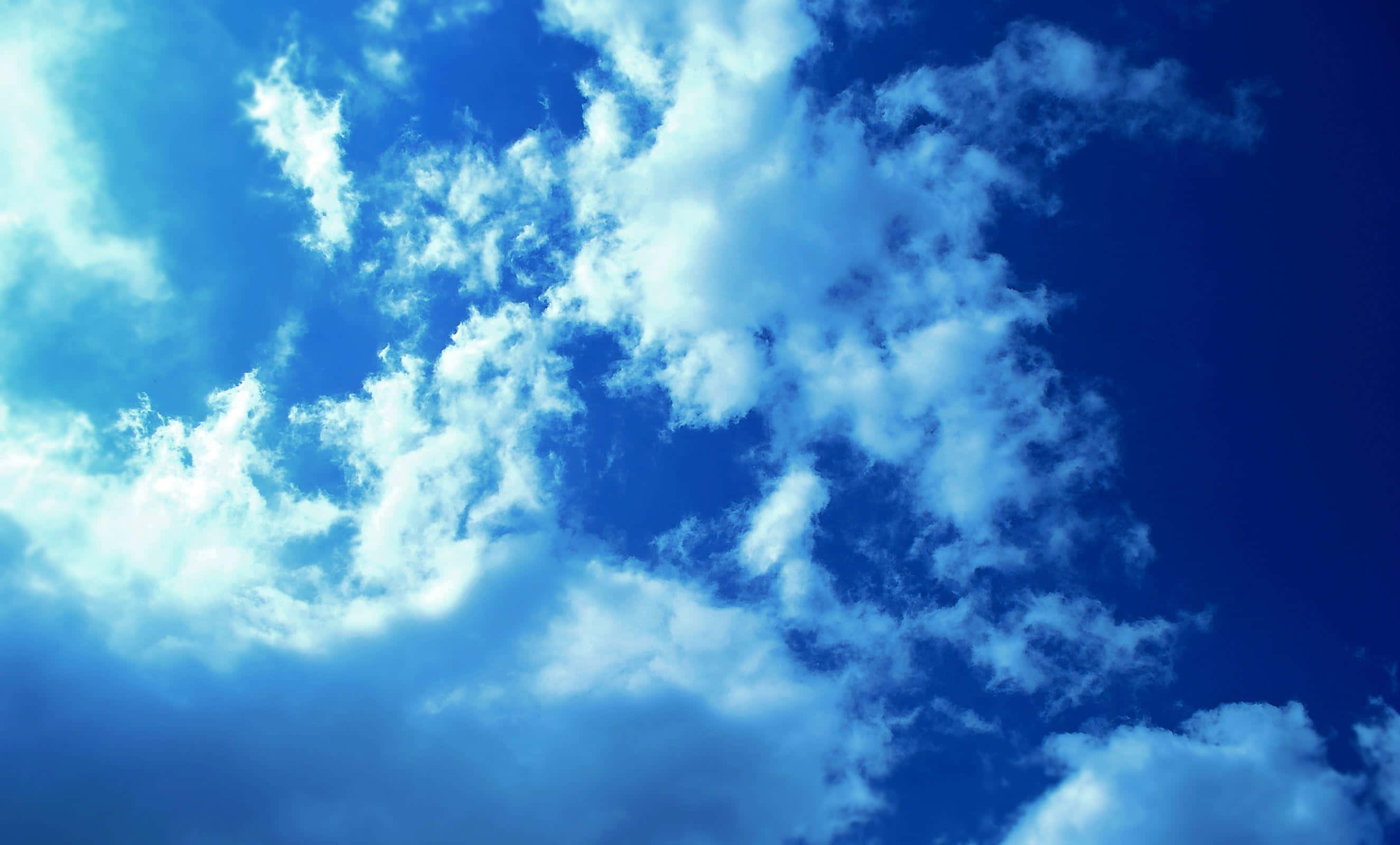 Sky Clouds 桌布 壁紙 — 充滿活力的藍天，佈滿蓬鬆的白雲，被明亮的陽光照射。