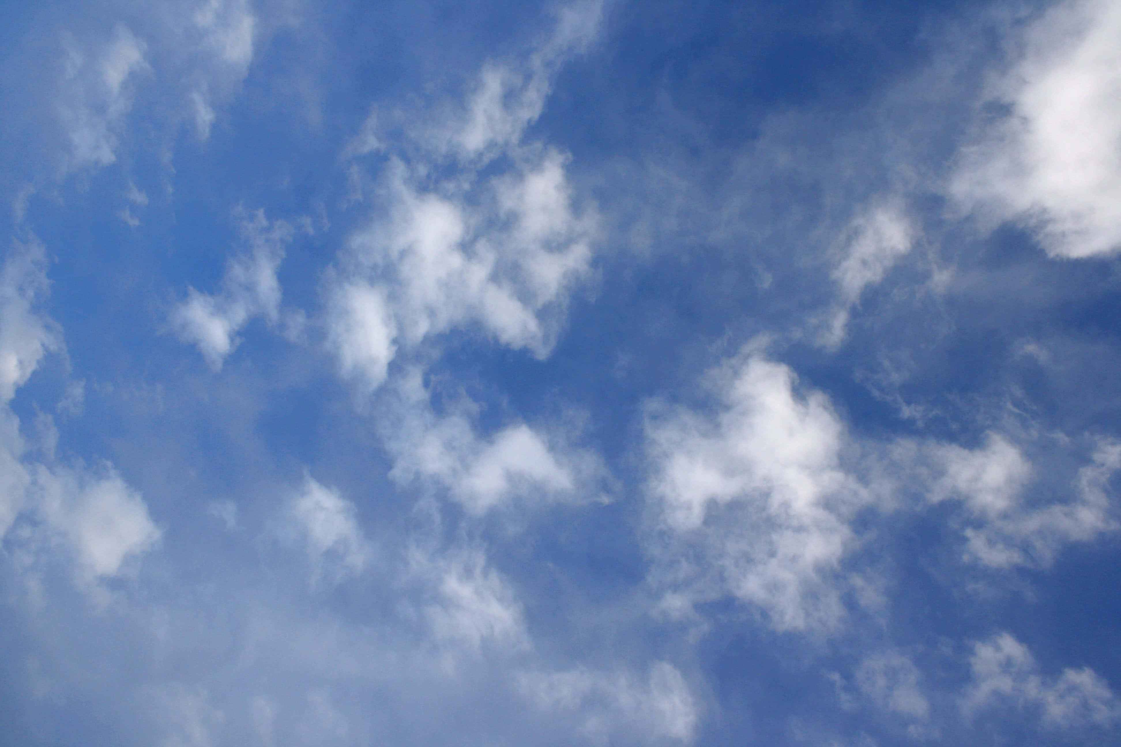 Blue Skies 桌布 壁紙 — 充滿活力的藍天，散佈著蓬鬆的白雲，在廣闊的天空中飄移。