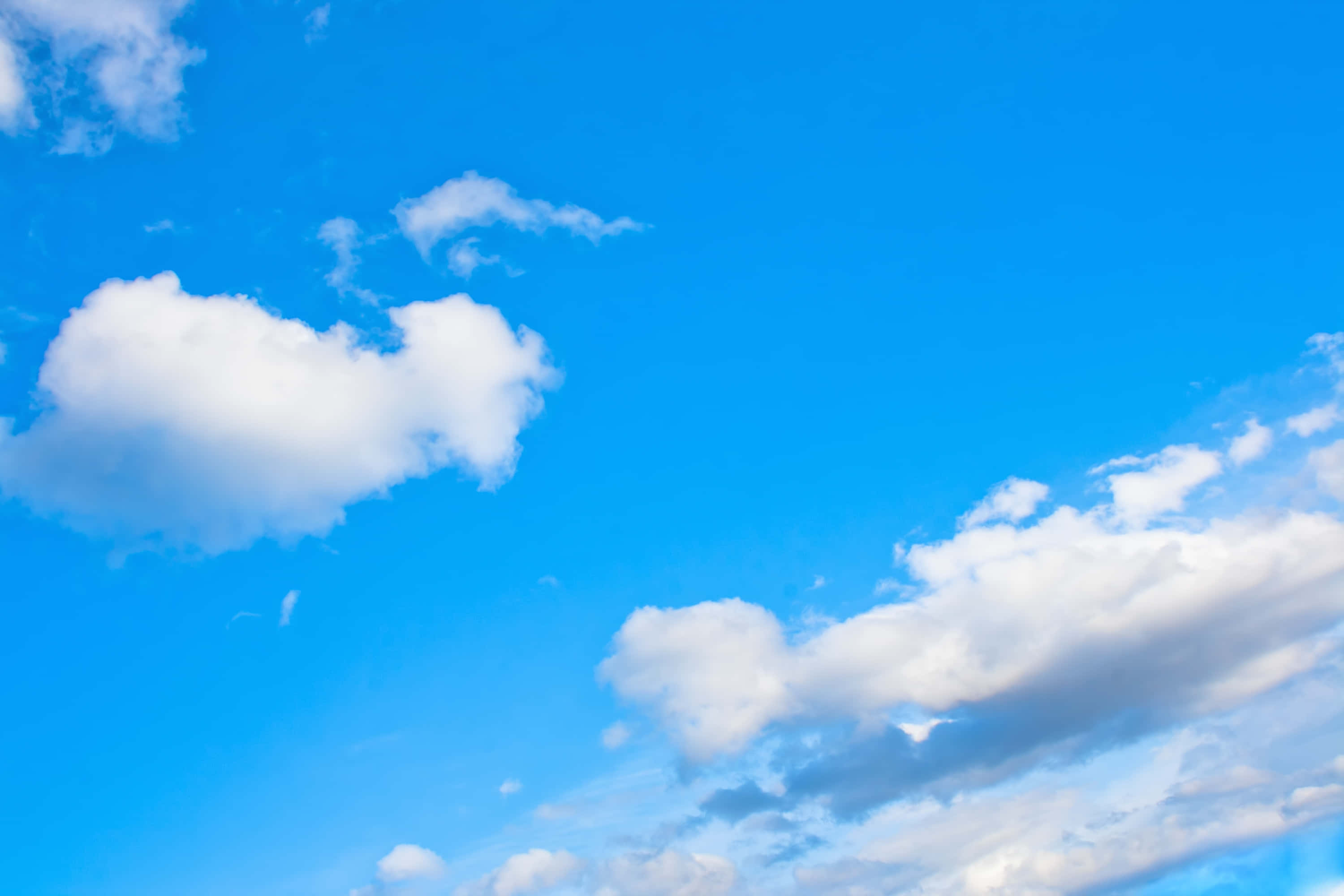 Blue Skies 桌布 壁紙 — 充滿活力的藍天，蓬鬆的白雲在晴朗的白天地平線上飄移。