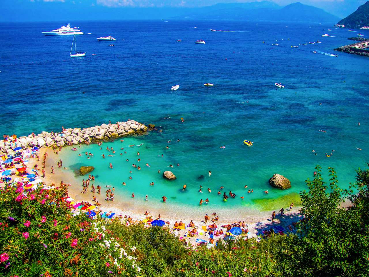 Capri 桌布 壁紙 — 充滿活力的藍綠色海水拍打著熙攘的海灘，沙灘上滿是享受日光浴的人們和船隻，天空湛藍清澈。
