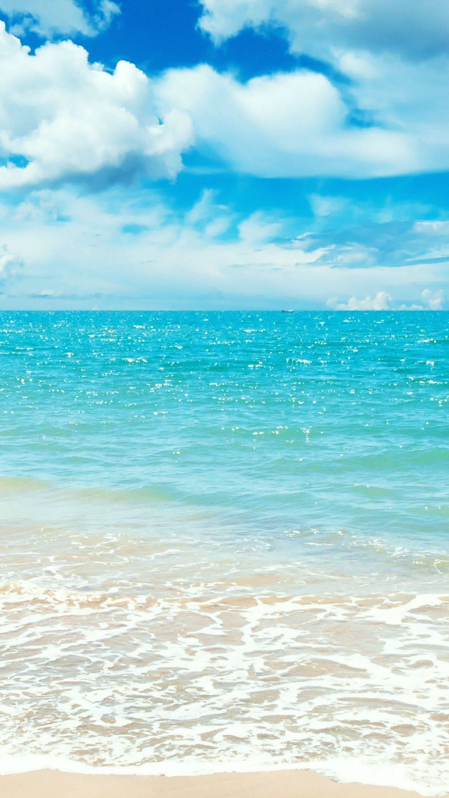 海洋 桌布 壁紙 — 充滿活力的藍綠色海浪輕輕拍打沙灘，天空湛藍，白雲朵朵。