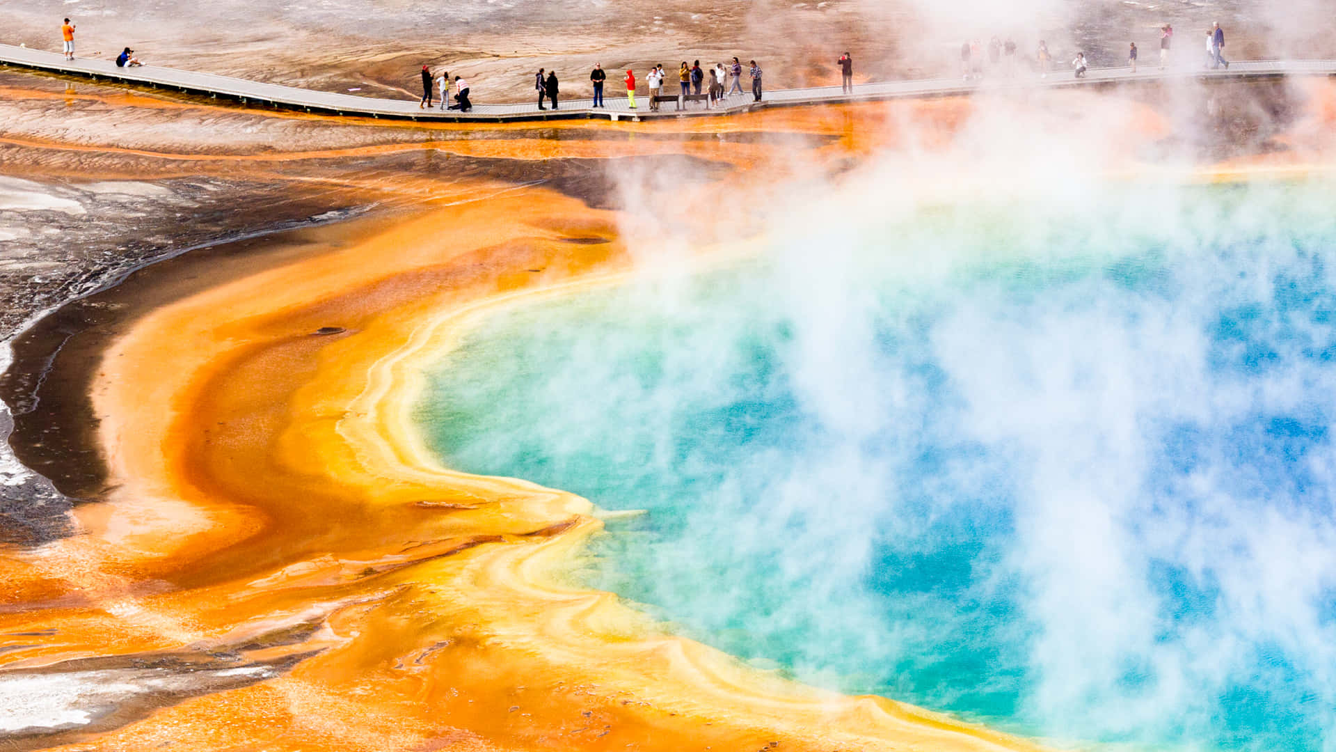Yellowstone 桌布 壁紙 — 充滿活力的藍綠色溫泉，蒸氣從色彩繽紛的橙色礦物梯田升起，遊客沿著木棧道行走。