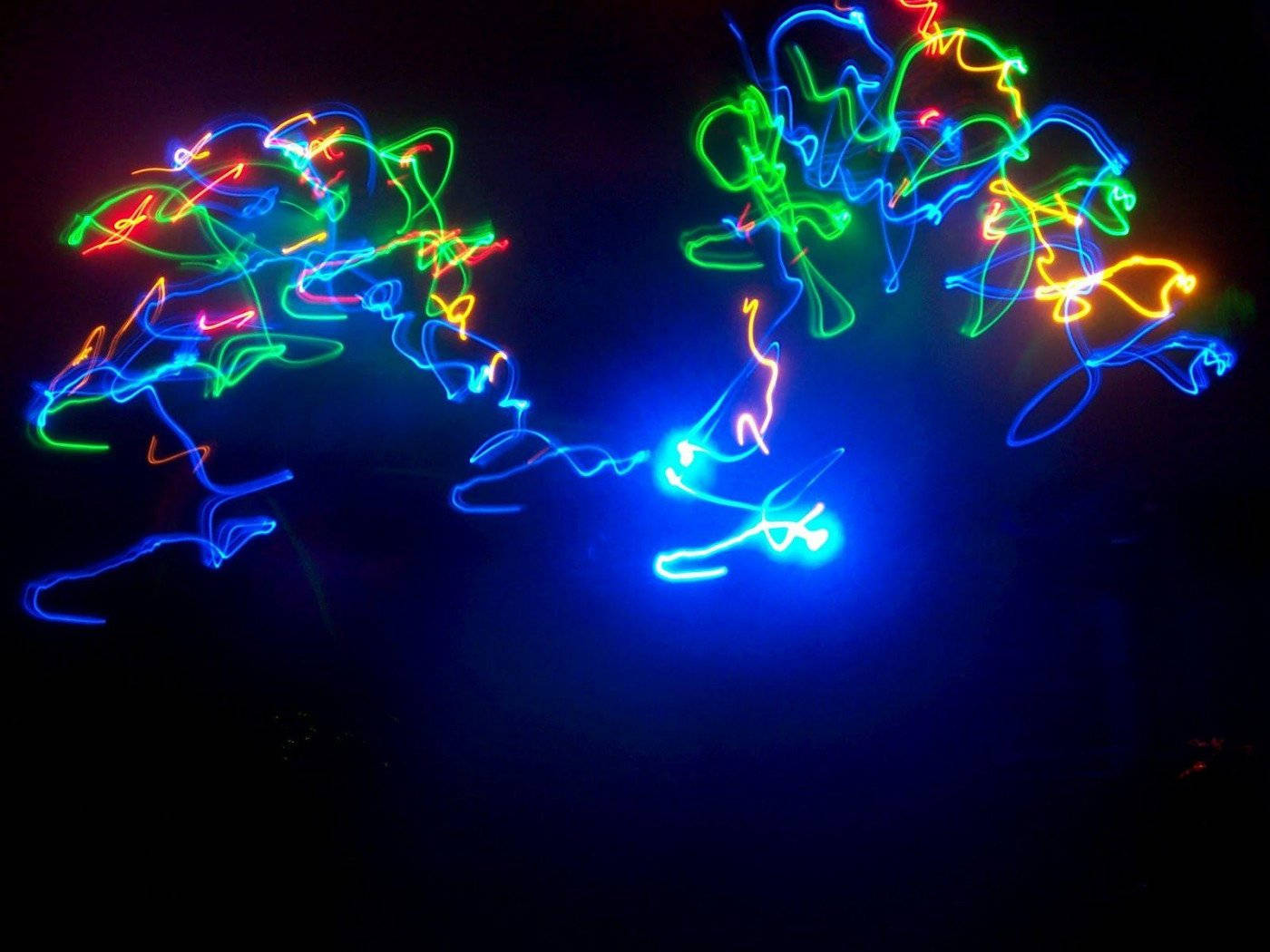 Neon Light 桌布 壁紙 — 充滿活力的藍色、綠色和黃色霓虹燈光軌跡在黑暗背景上旋轉，形成抽象的發光形狀。