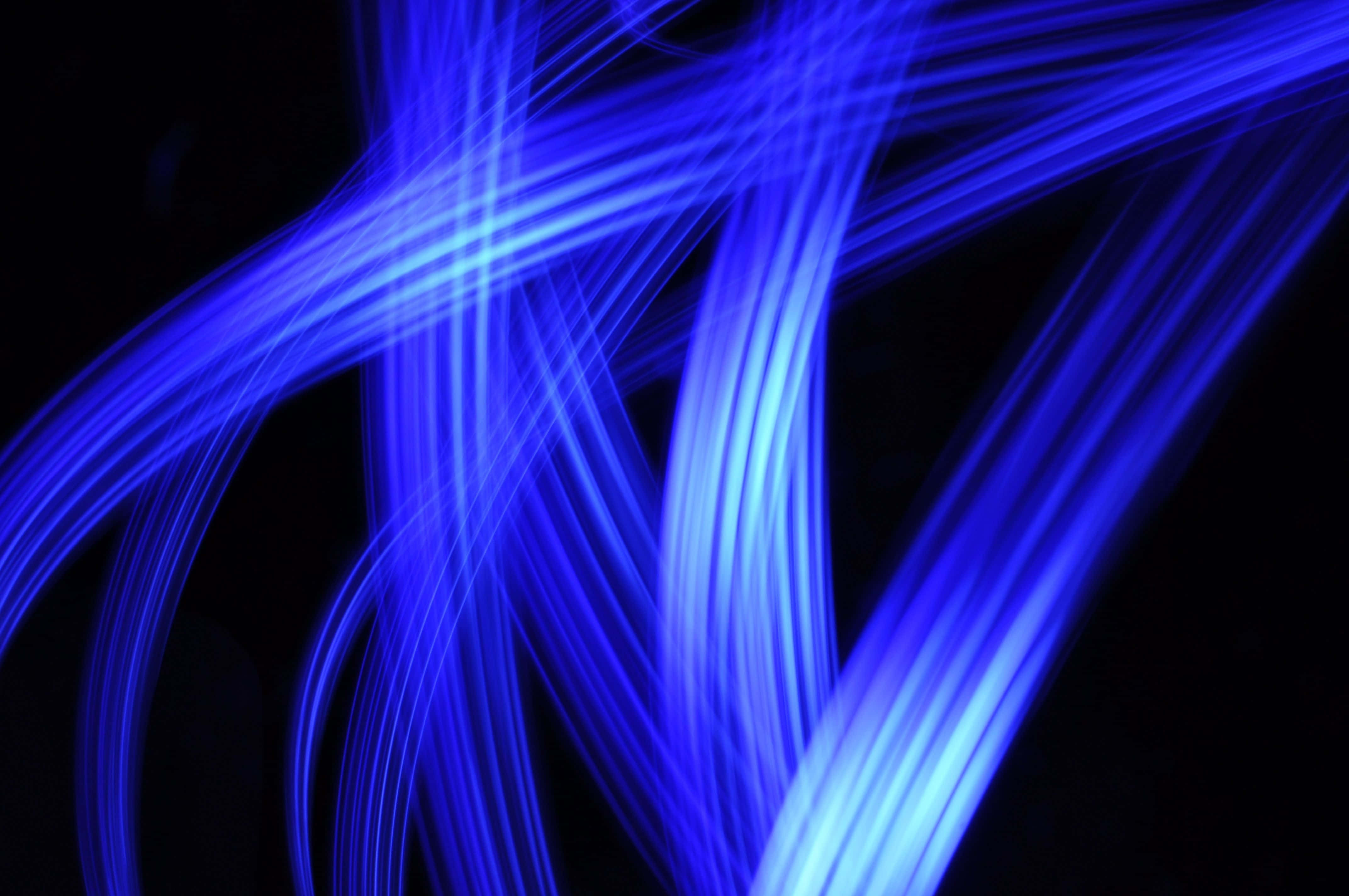 flashy 桌布 壁紙 — 充滿活力的藍色光軌劃過漆黑的背景，形成動態的抽象圖案。