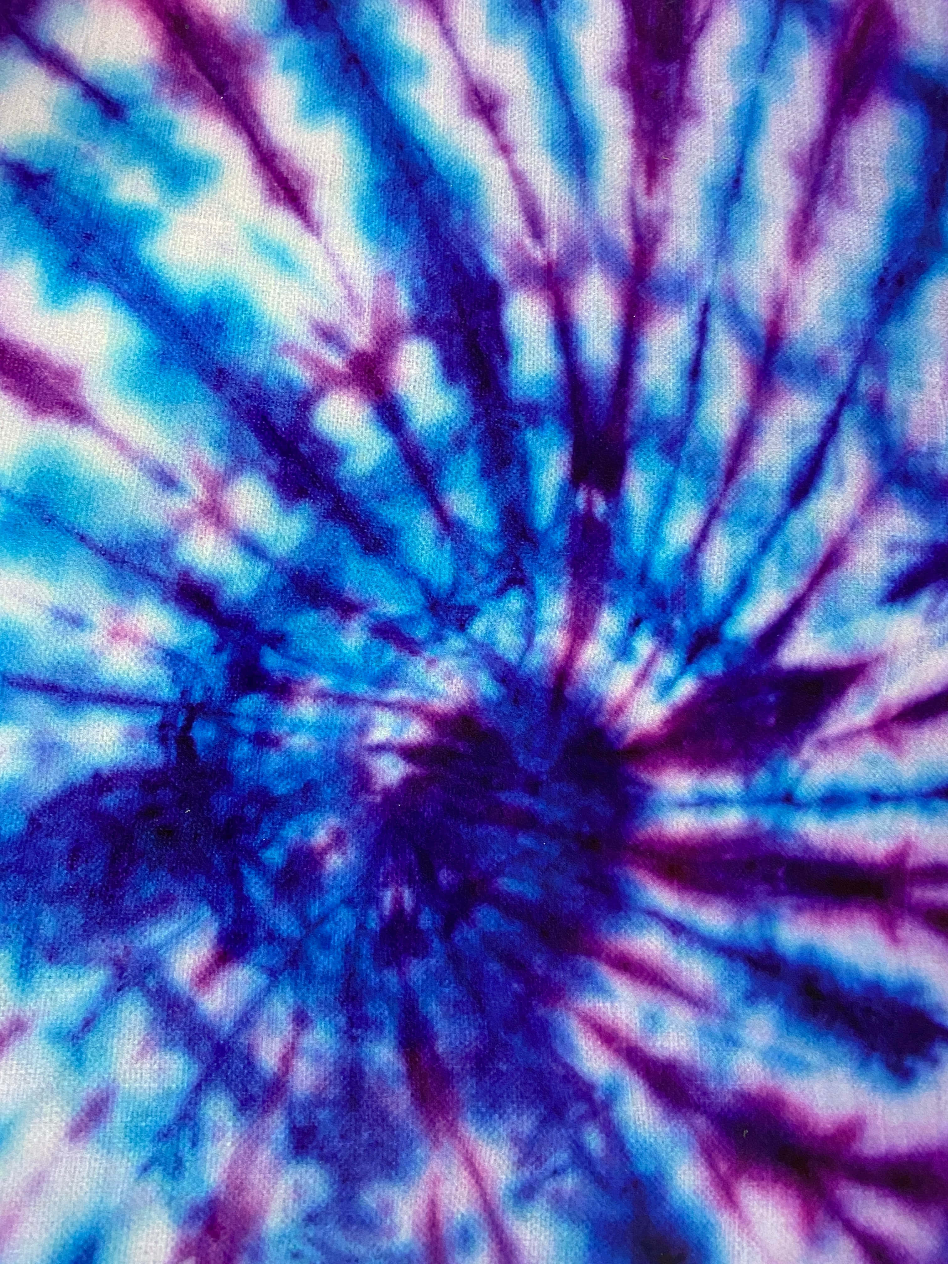 Blue Tie Dye 桌布 壁紙 — 充滿活力的藍色和紫色紮染從有紋理布料上的中心點向外輻射。