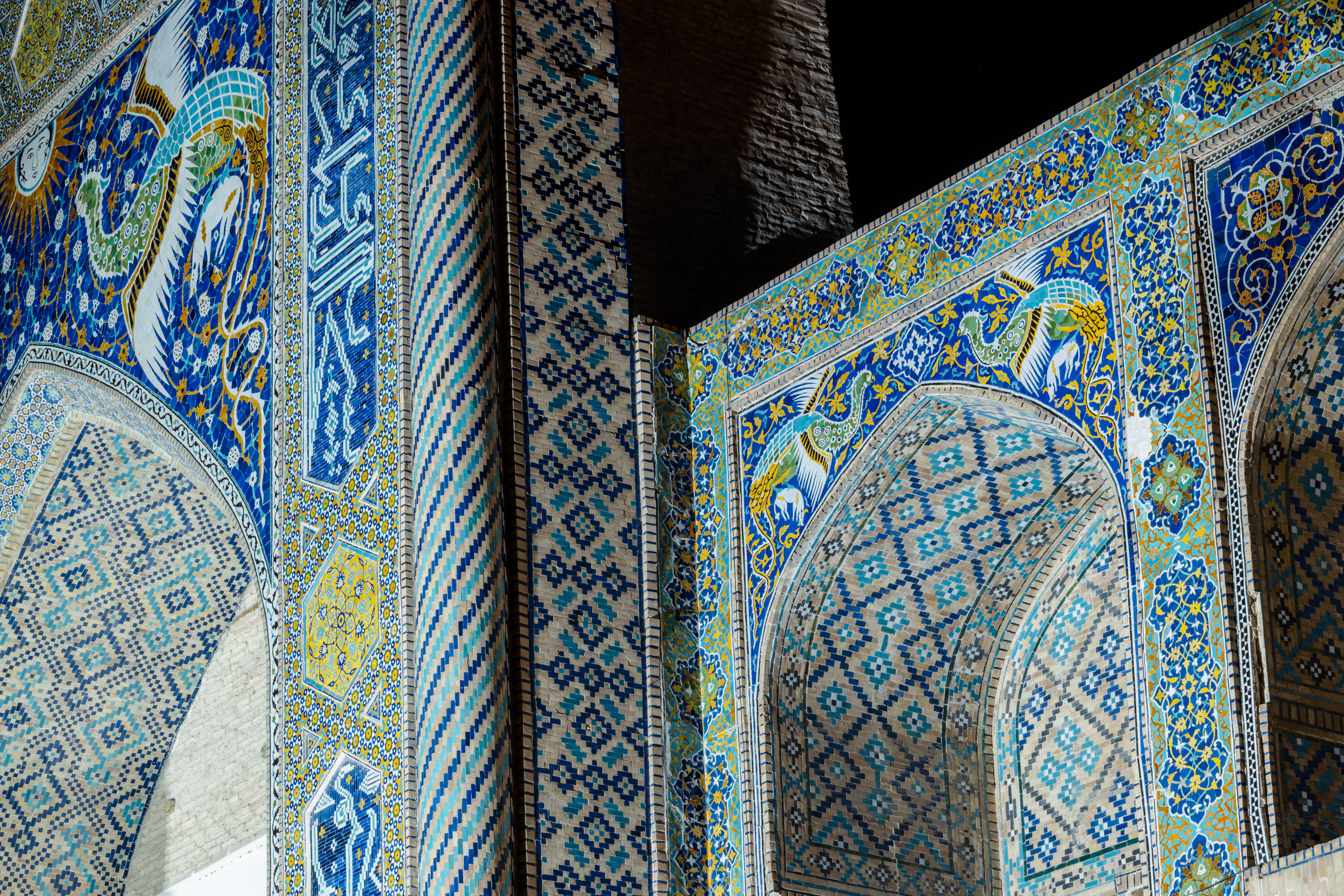Uzbekistan 桌布 壁紙 — 充滿活力的藍色和金色瓷磚裝飾著歷史悠久的清真寺內部錯綜複雜的伊斯蘭拱門和柱子。