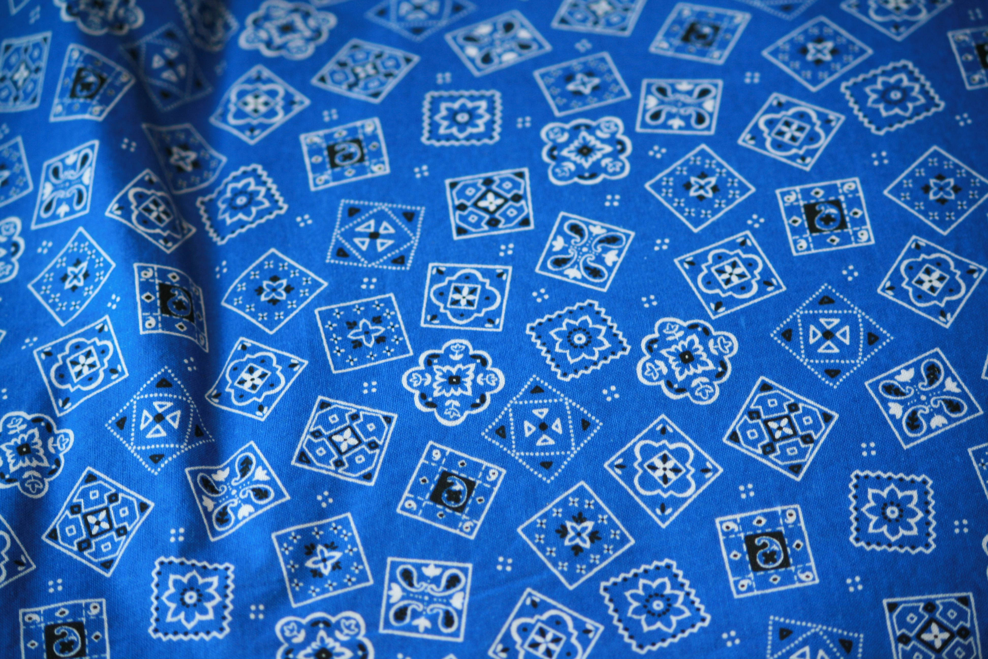 bandana 桌布 壁紙 — 充滿活力的藍色布料特寫，帶有複雜的白色和黑色幾何花卉圖案。