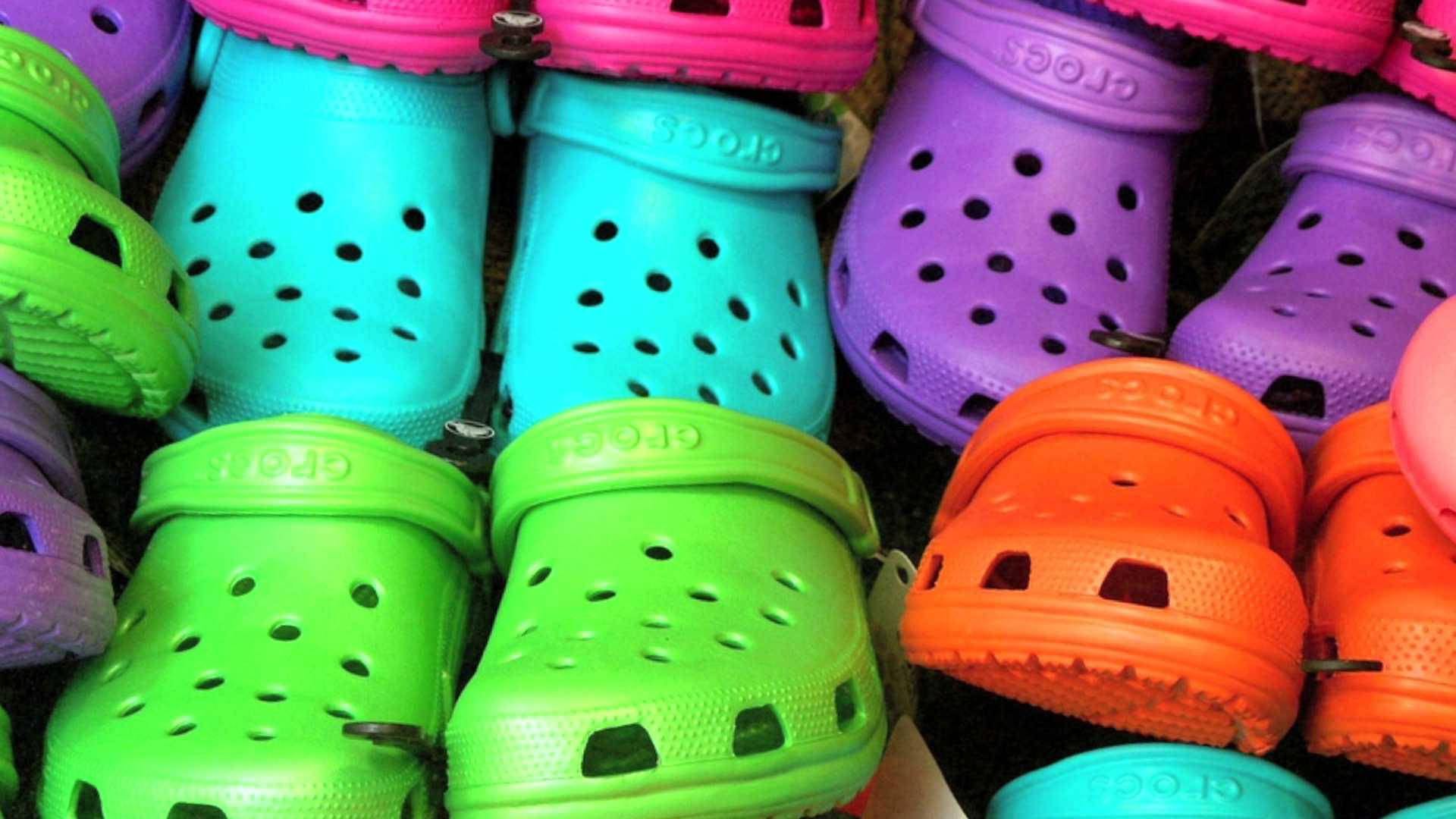 Crocs 桌布 壁紙 — 充滿活力的螢光色Crocs木屐，以萊姆綠、青色、洋紅色和橙色排列，呈現色彩繽紛的特寫展示。