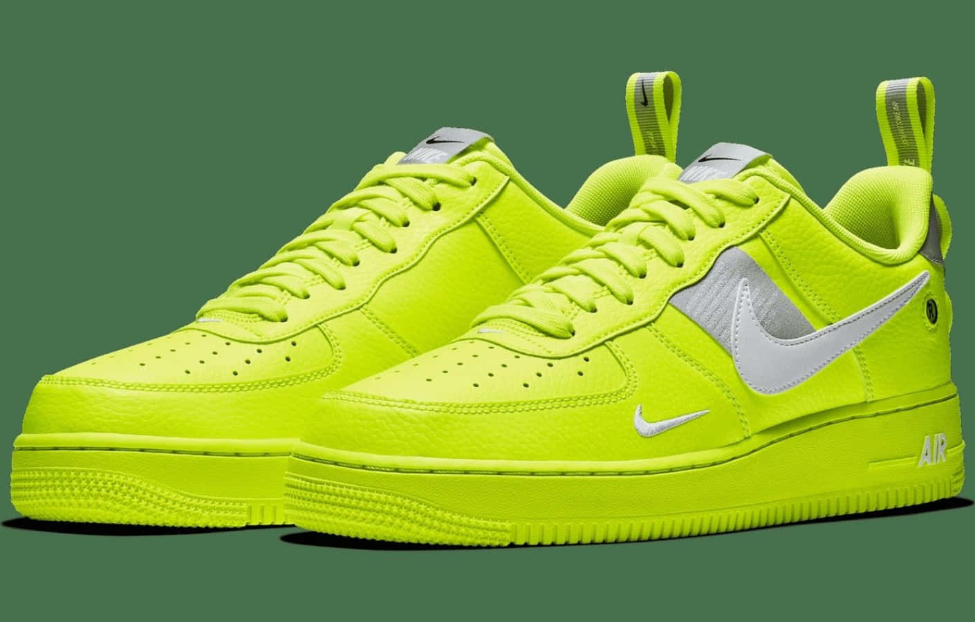 桌布 壁紙 — 充滿活力的螢光黃色Nike Air Force 1運動鞋，帶有銀色點綴，展示在純綠色背景上。