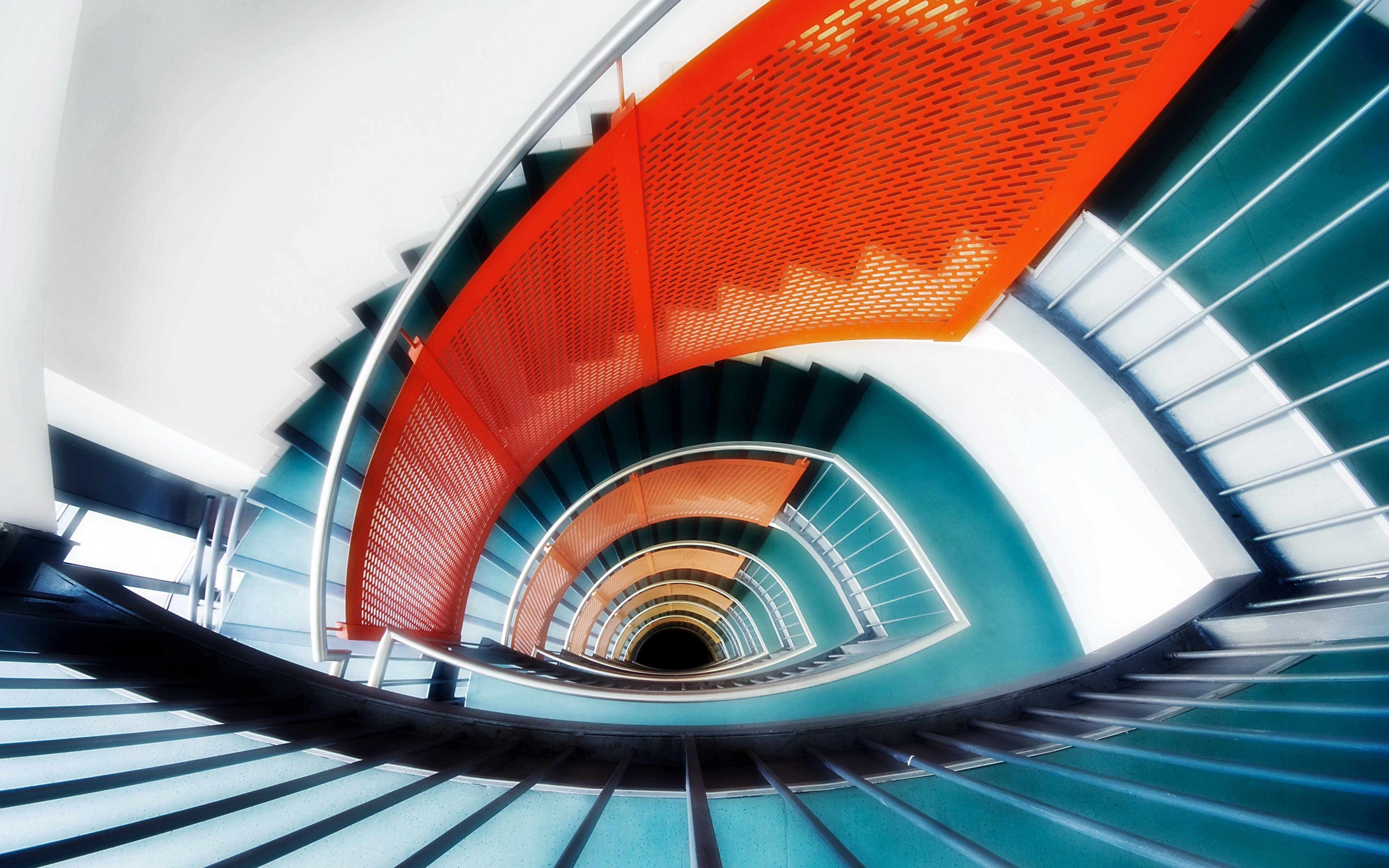Architecture 桌布 壁紙 — 充滿活力的螺旋樓梯，帶有醒目的紅色和藍綠色部分，在現代建築奇蹟中向上彎曲。