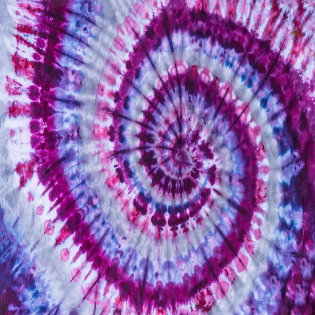 Purple Tie Dye 桌布 壁紙 — 充滿活力的螺旋紮染圖案從中心向外輻射，在白色布料上呈現洋紅紫和藍色調。