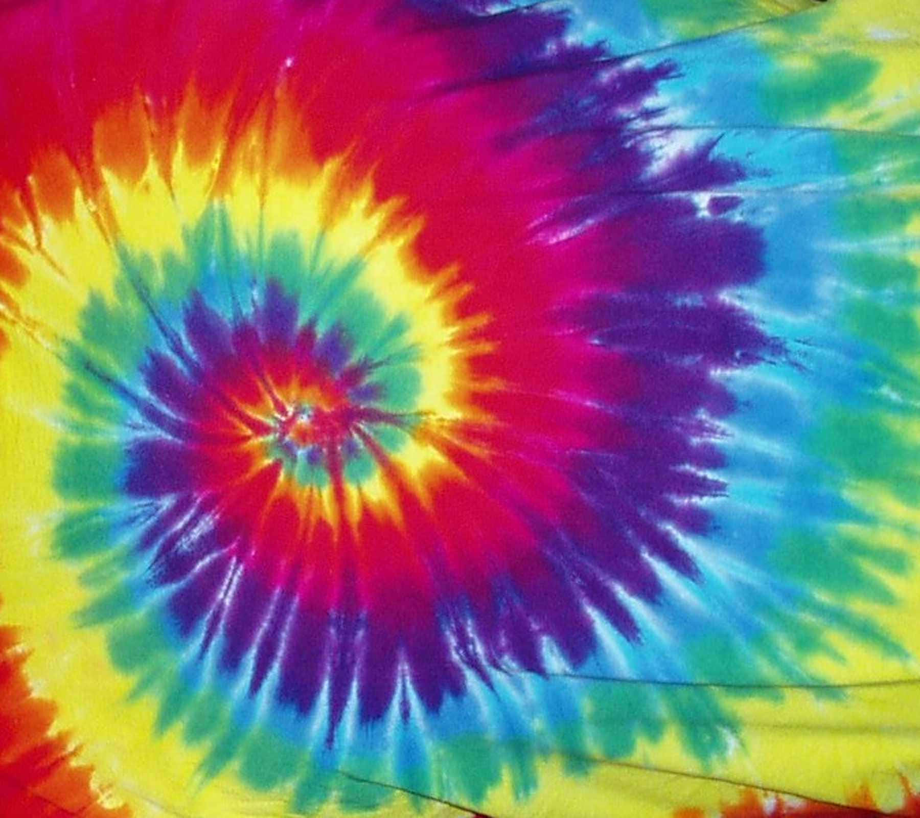 High Resolution Tie Dye 桌布 壁紙 — 充滿活力的螺旋紮染圖案從中心向外輻射，帶有鮮明的紅、黃、藍、綠和紫色調。