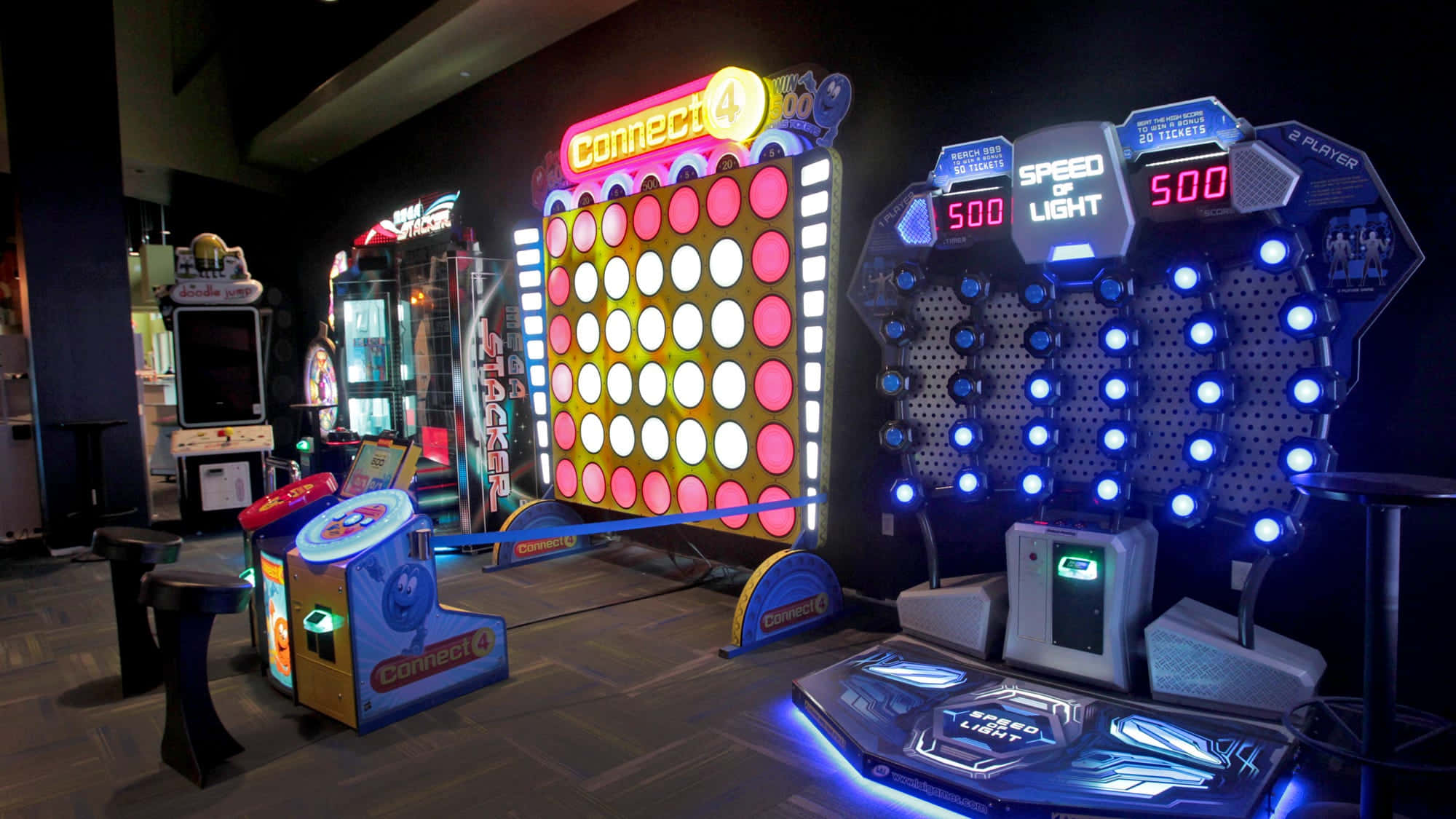 Arcade Games 桌布 壁紙 — 充滿活力的街機遊戲在昏暗的遊戲廳中閃爍著霓虹燈光，配備Connect 4和Speed of Light機台。