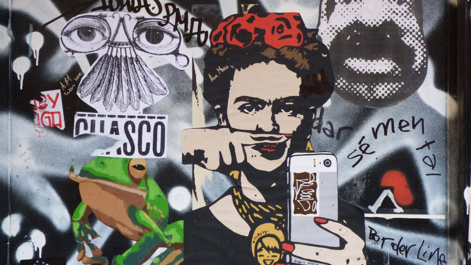 frida 桌布 壁紙 — 充滿活力的街頭藝術壁畫，描繪芙烈達·卡蘿在塗鴉貼紙和普普藝術元素環繞下自拍。