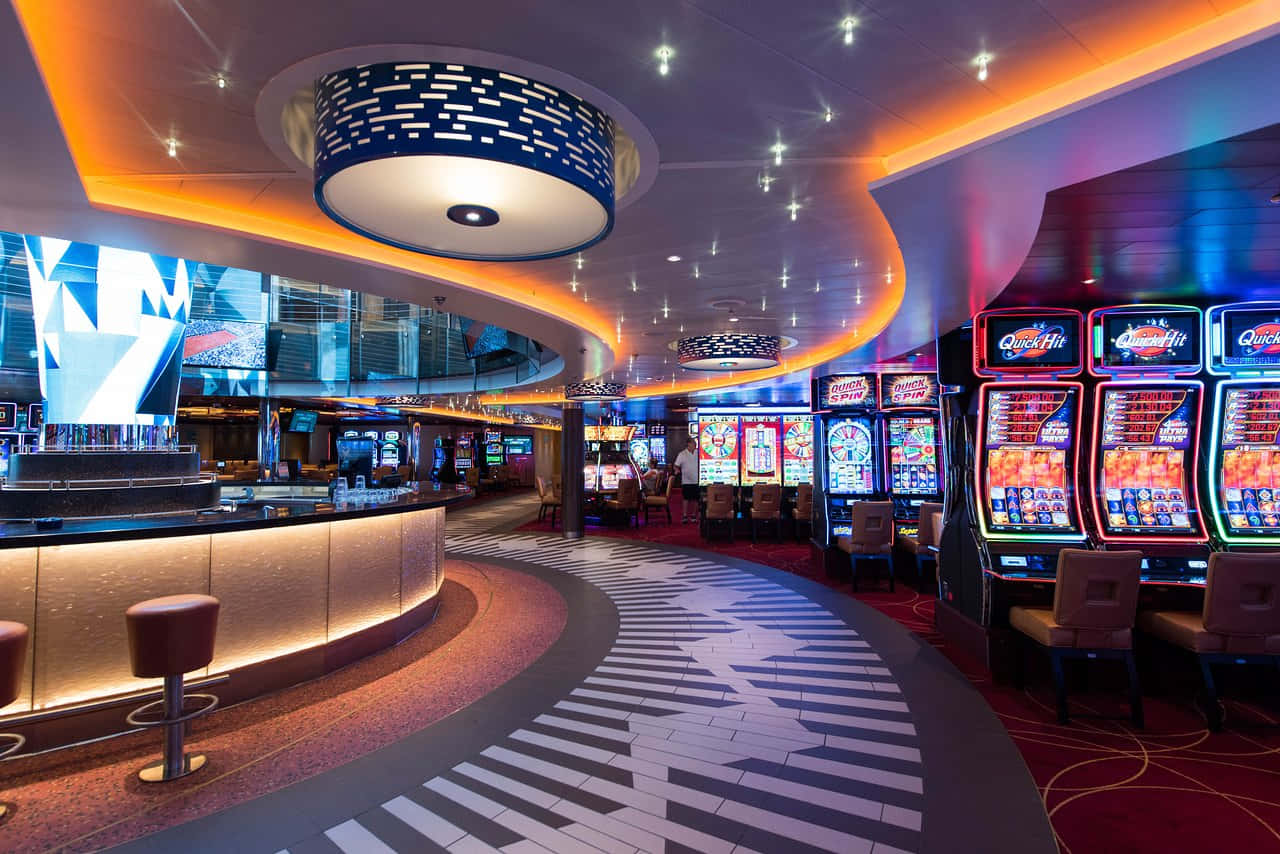 Carnival Conquest 桌布 壁紙 — 充滿活力的賭場內部，設有發光的老虎機和彩色天花板燈下的弧形酒吧。