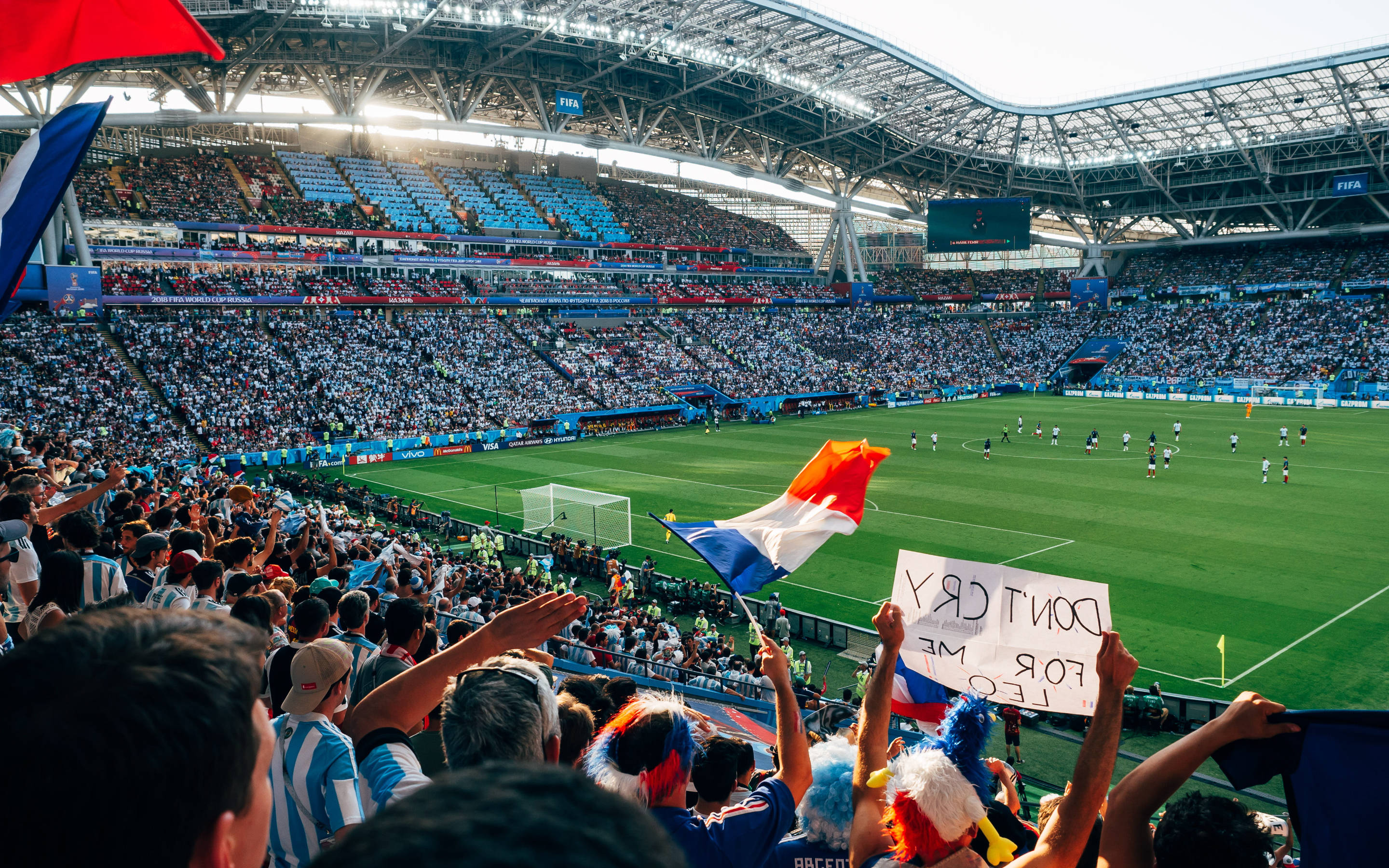 France Flag 桌布 壁紙 — 充滿活力的足球迷在日間比賽中，在擠滿人的現代體育館揮舞旗幟和舉起標語牌。