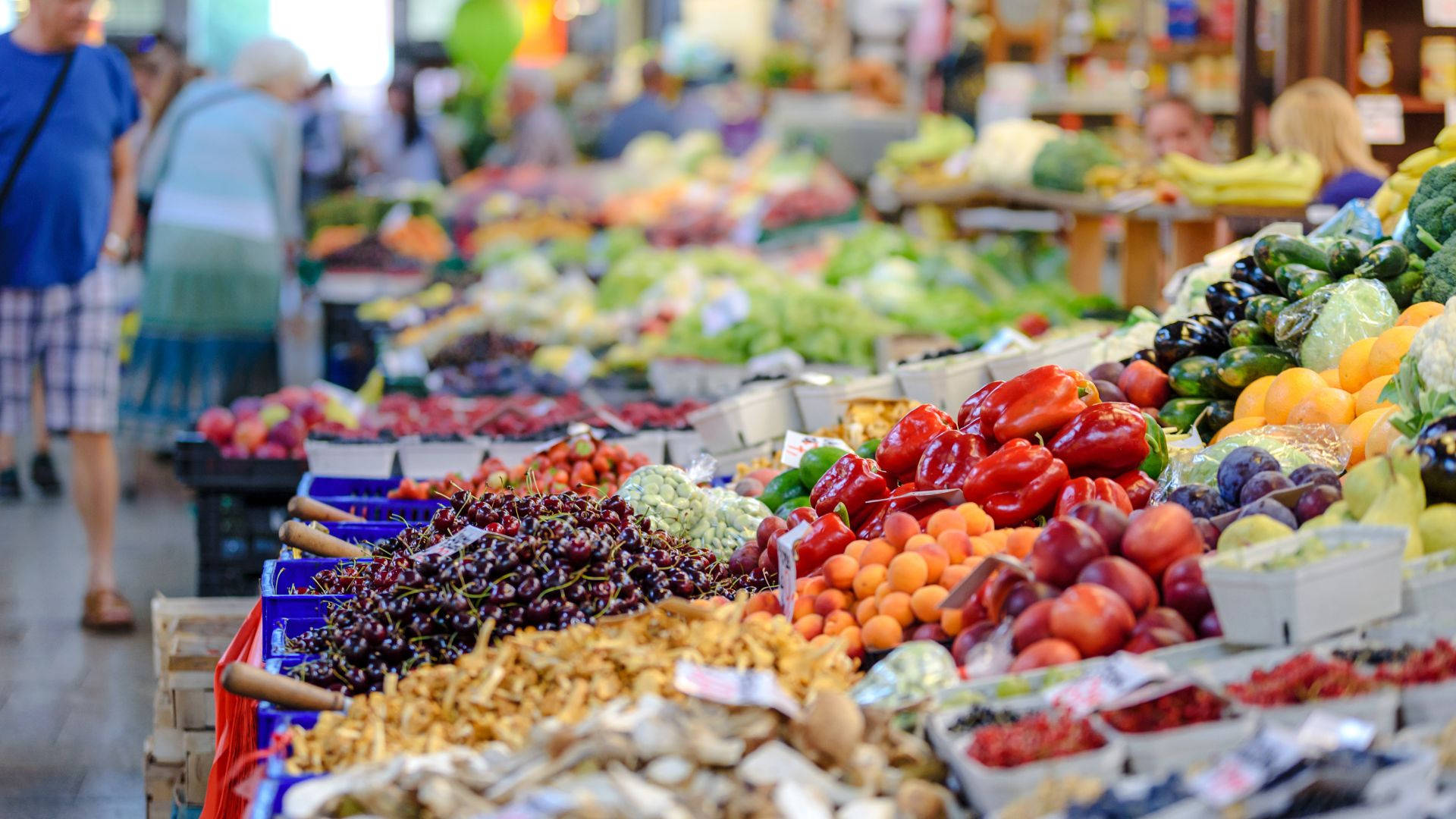 Fruits 桌布 壁紙 — 充滿活力的農產品攤位在熱鬧的農夫市集上堆滿了色彩繽紛的水果和蔬菜。