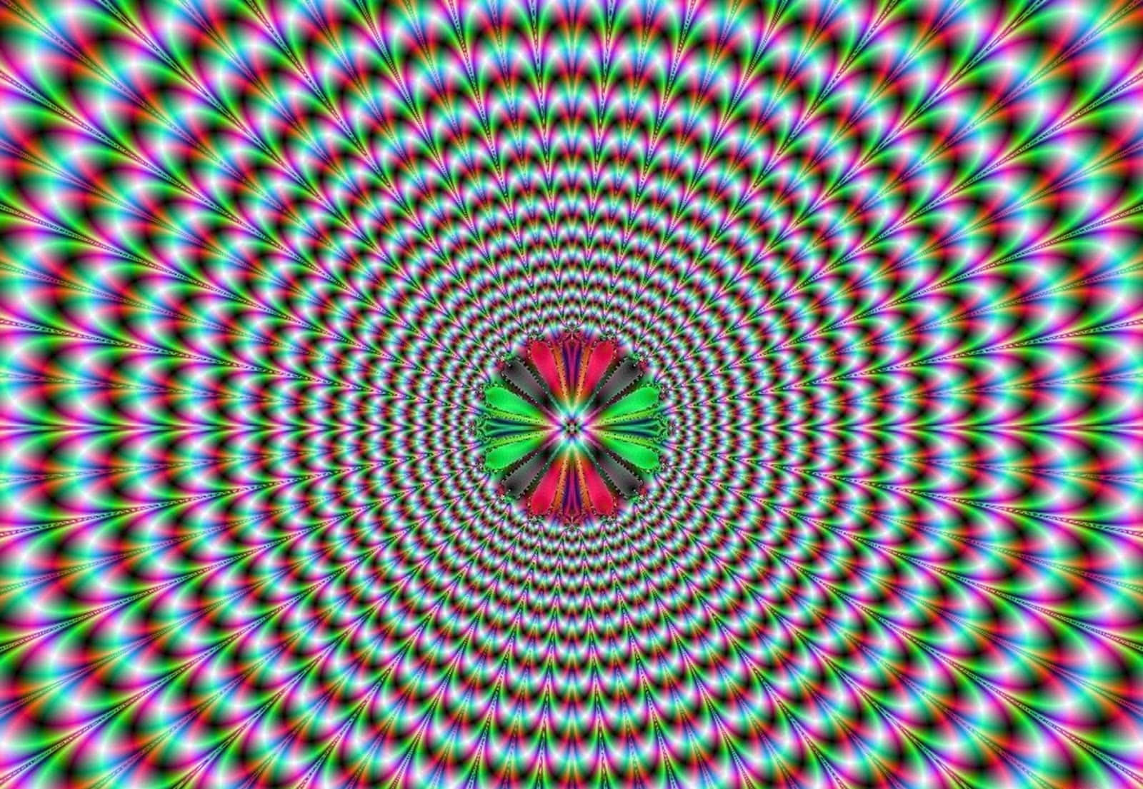 彩色動圖 桌布 壁紙 — 充滿活力的迷幻萬花筒，帶有放射狀彩虹圖案，匯聚在中央的幾何花朵上。
