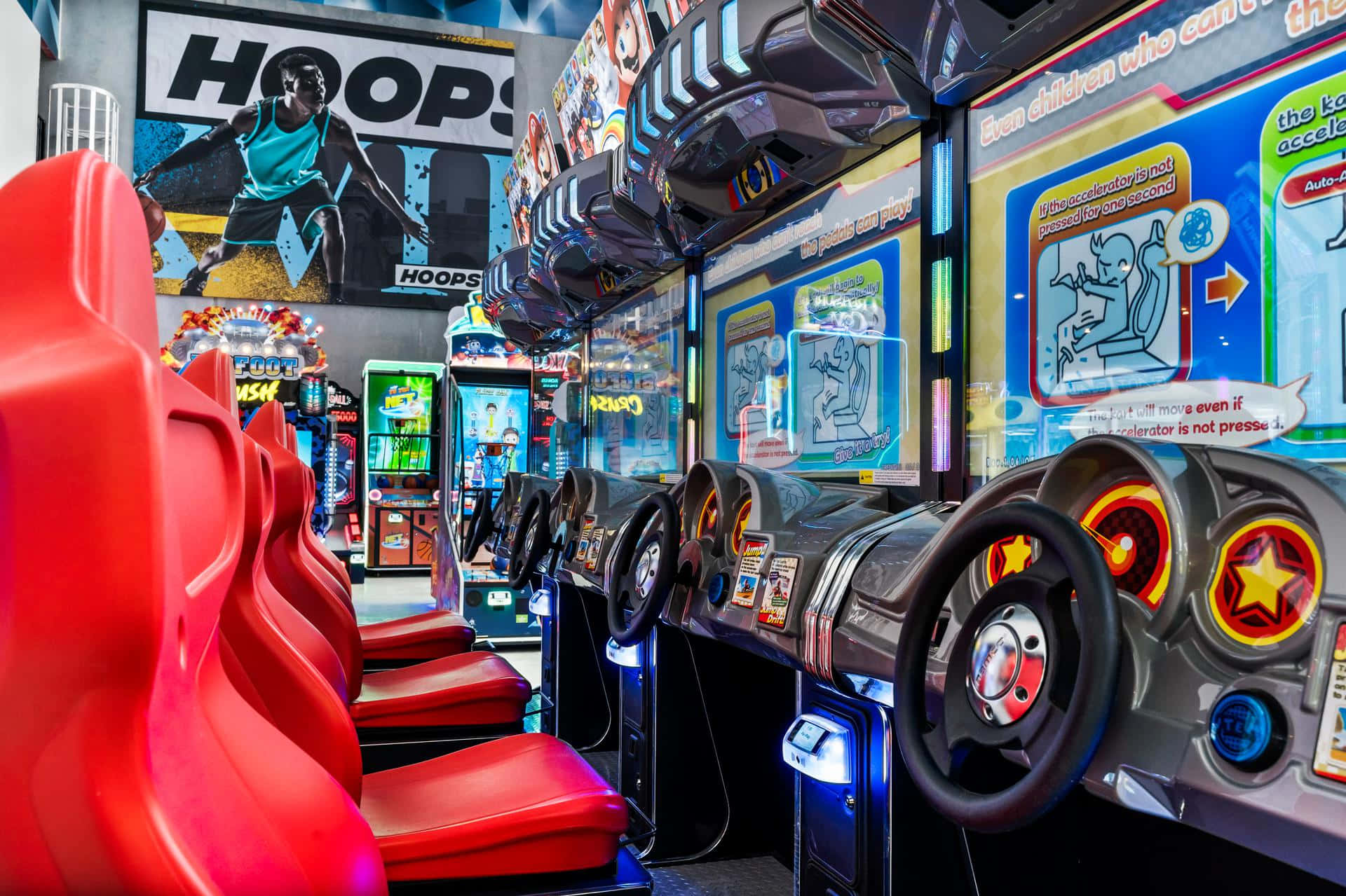Arcade Games 桌布 壁紙 — 充滿活力的遊戲機室，設有紅色賽車座椅和發光方向盤遊戲機，在彩色霓虹燈下。