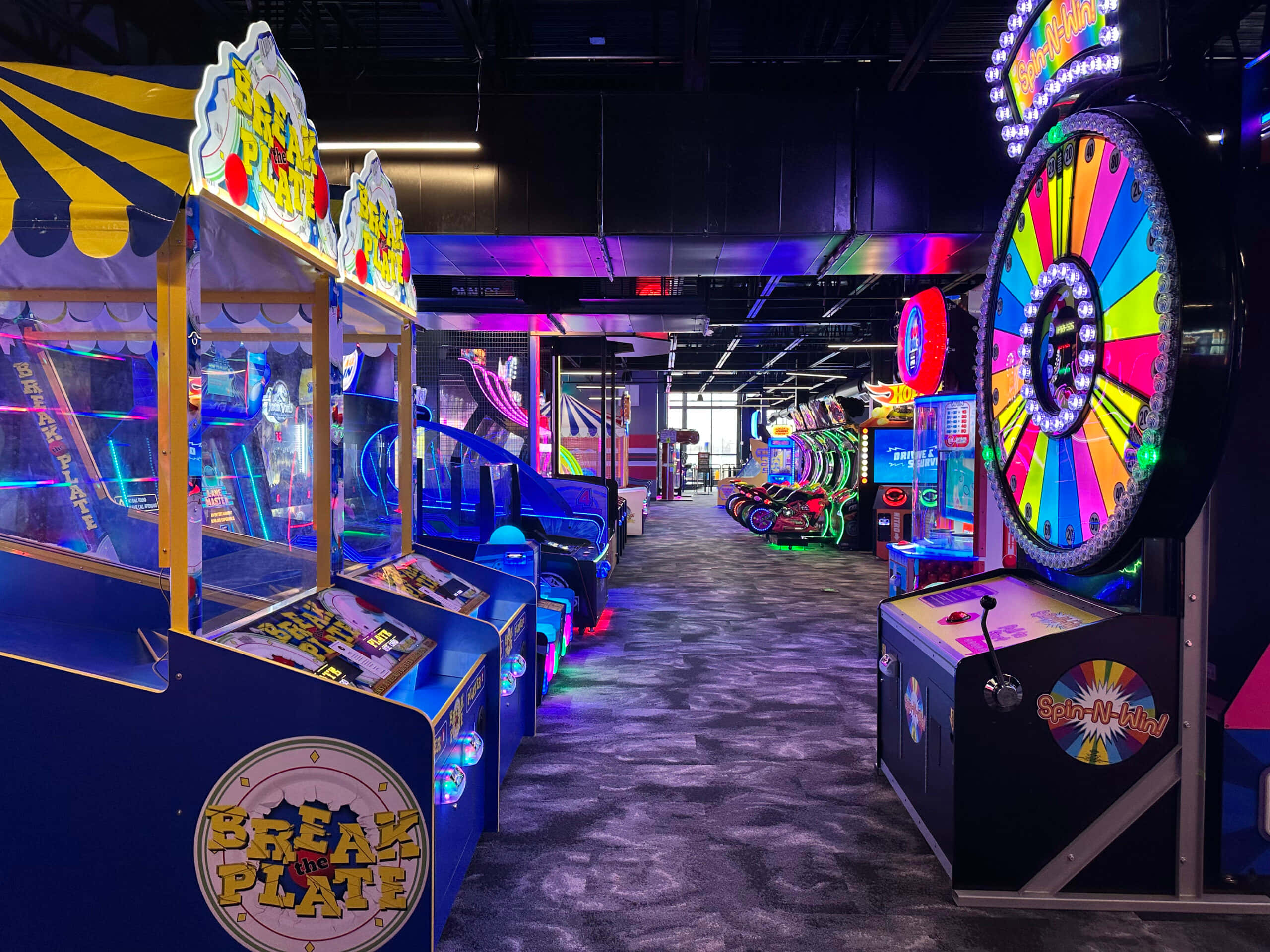 Arcade Games 桌布 壁紙 — 充滿活力的遊戲機走廊，在黑暗天花板下閃爍著霓虹燈光和色彩繽紛的遊戲機。