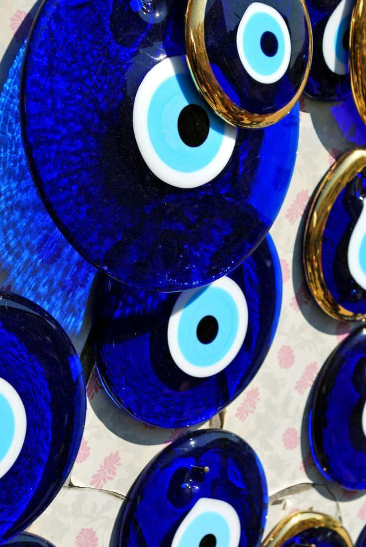 Evil Eye 桌布 壁紙 — 充滿活力的鈷藍色邪眼飾物，帶有金色邊框和白色同心圓，放置在花卉圖案表面上。