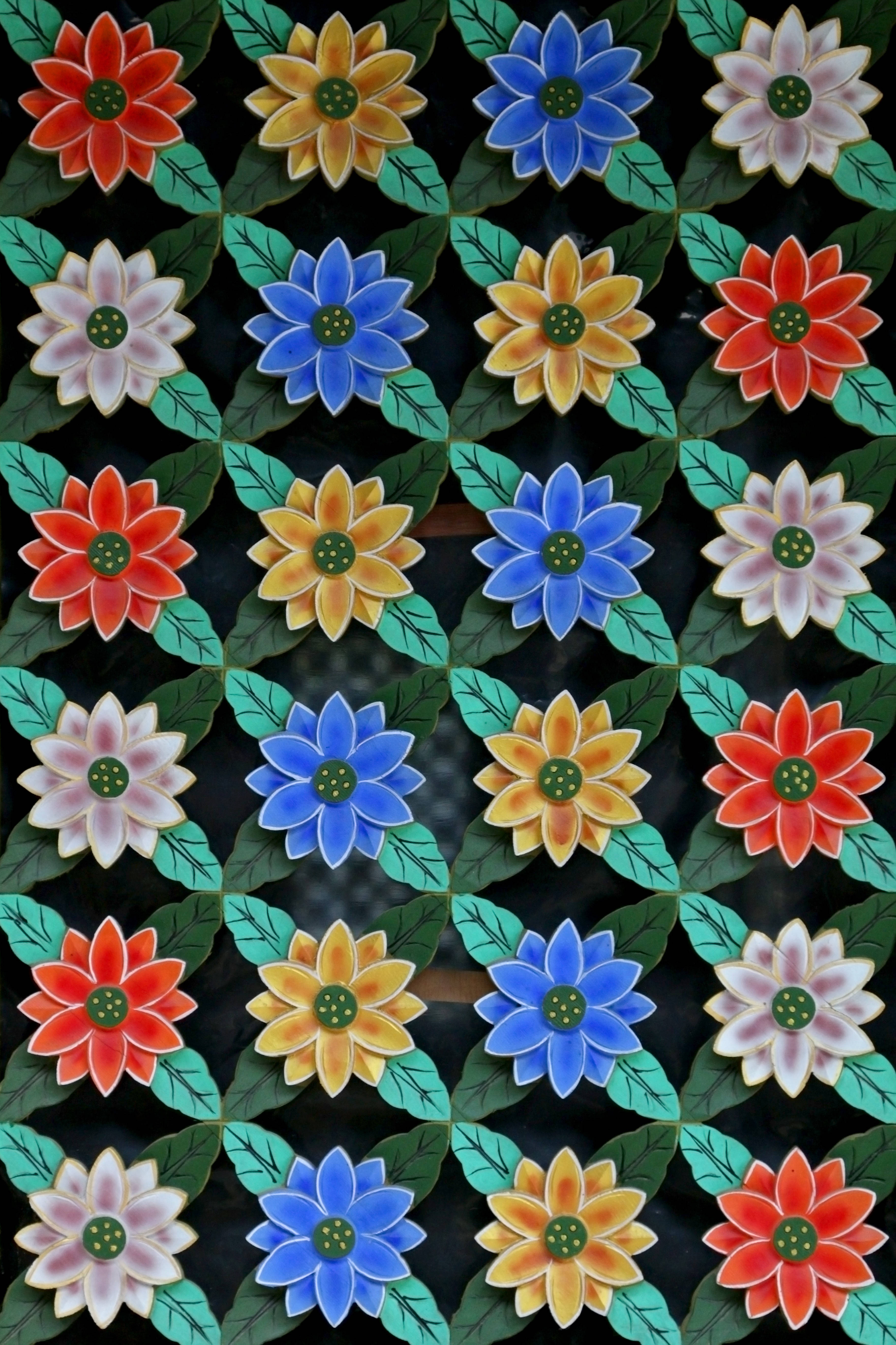 花卉 桌布 壁紙 — 充滿活力的陶瓷磚展示重複的彩色花朵，有紅色、黃色、藍色和粉紅色，帶有綠色葉子，背景為深色。