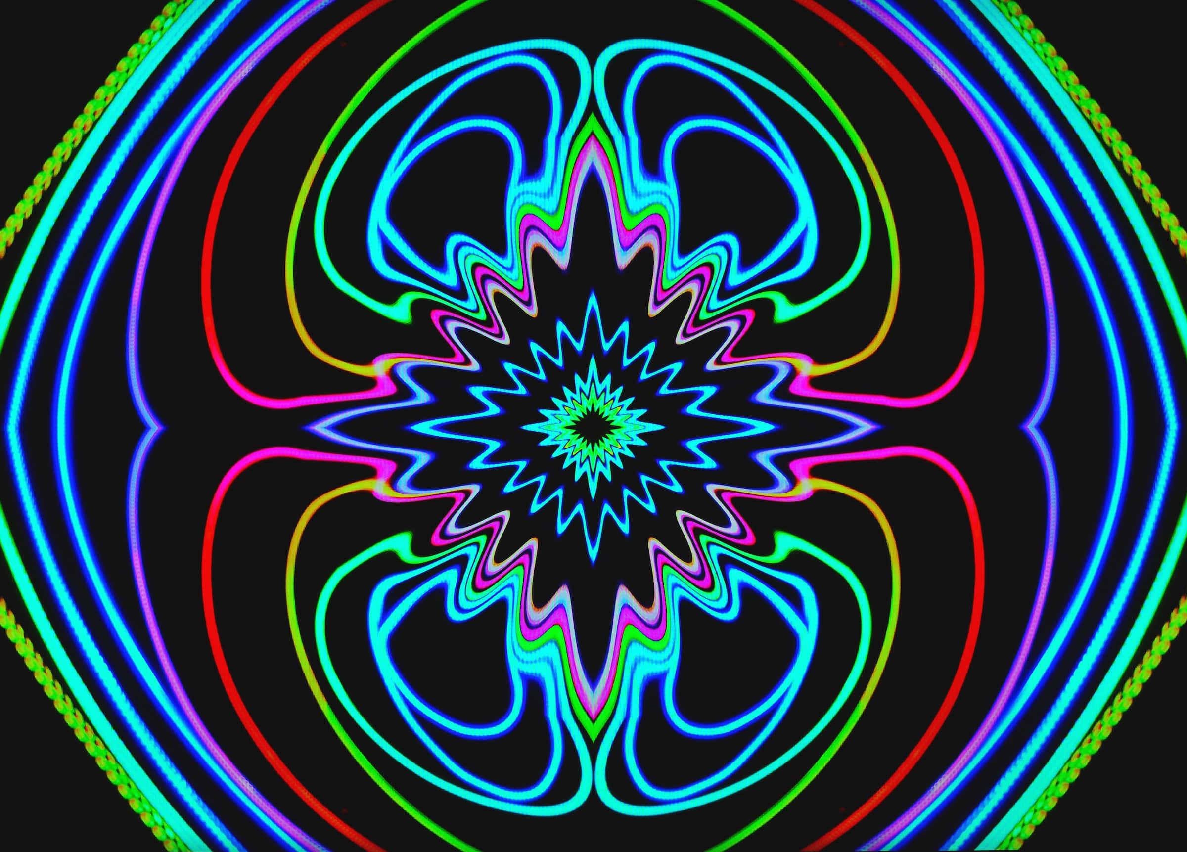 Psychedelic Neon Lights 桌布 壁紙 — 充滿活力的霓虹彩虹線條在黑色背景上旋轉成催眠的對稱圖案。