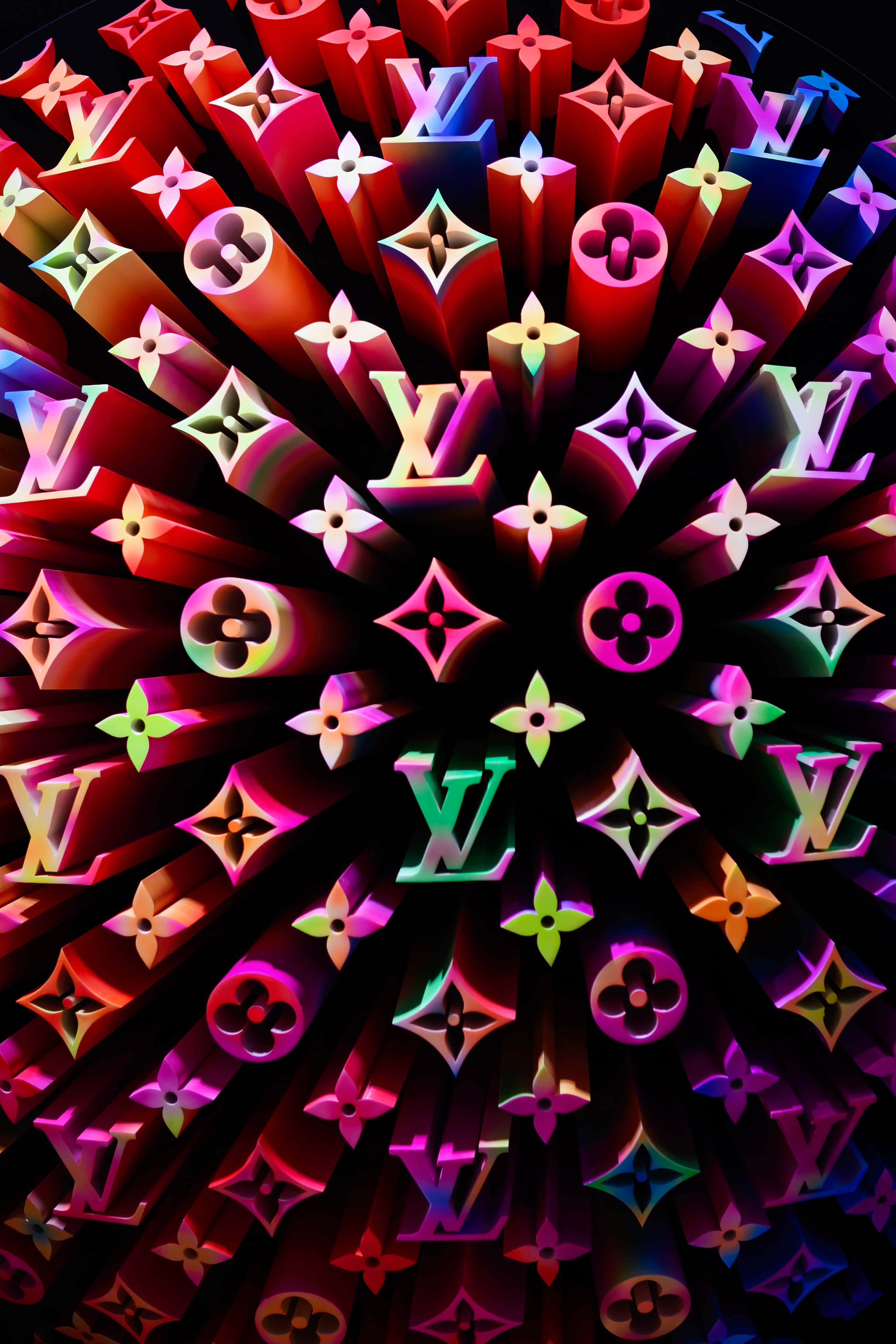 Louis Vuitton Pattern 桌布 壁紙 — 充滿活力的霓虹標誌在黑色背景上徑向爆炸，形成耀眼的數位圖案。