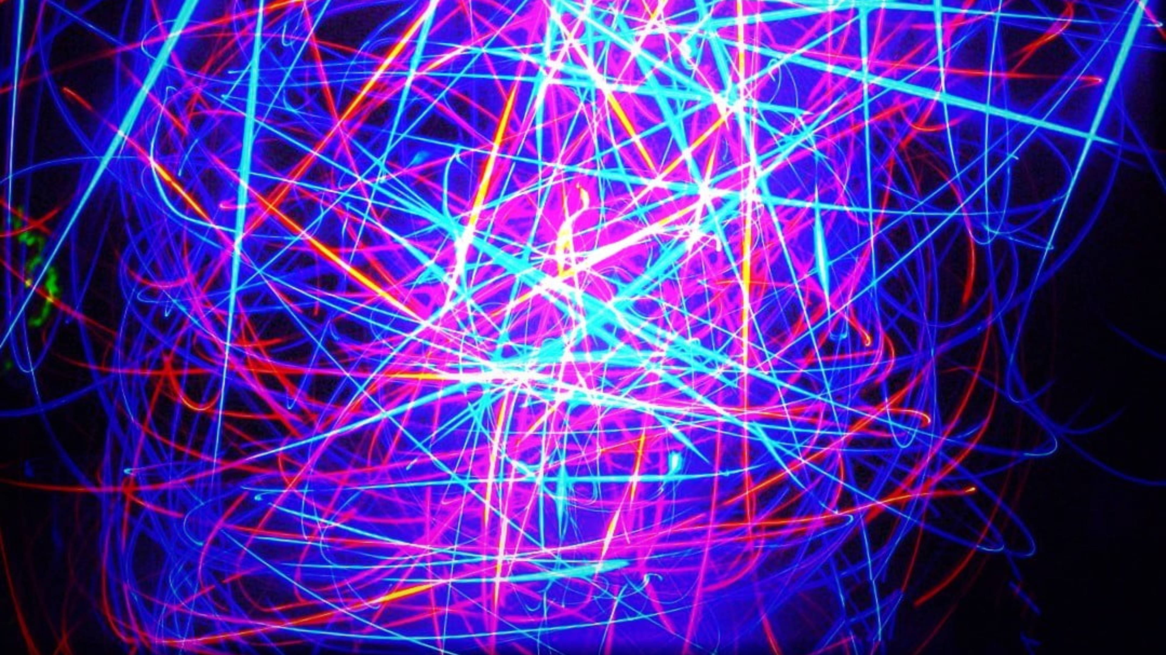 lights 桌布 壁紙 — 充滿活力的霓虹燈光軌跡，以電光藍、粉紅和橙色在黑色虛空中以混亂的抽象運動劃過。