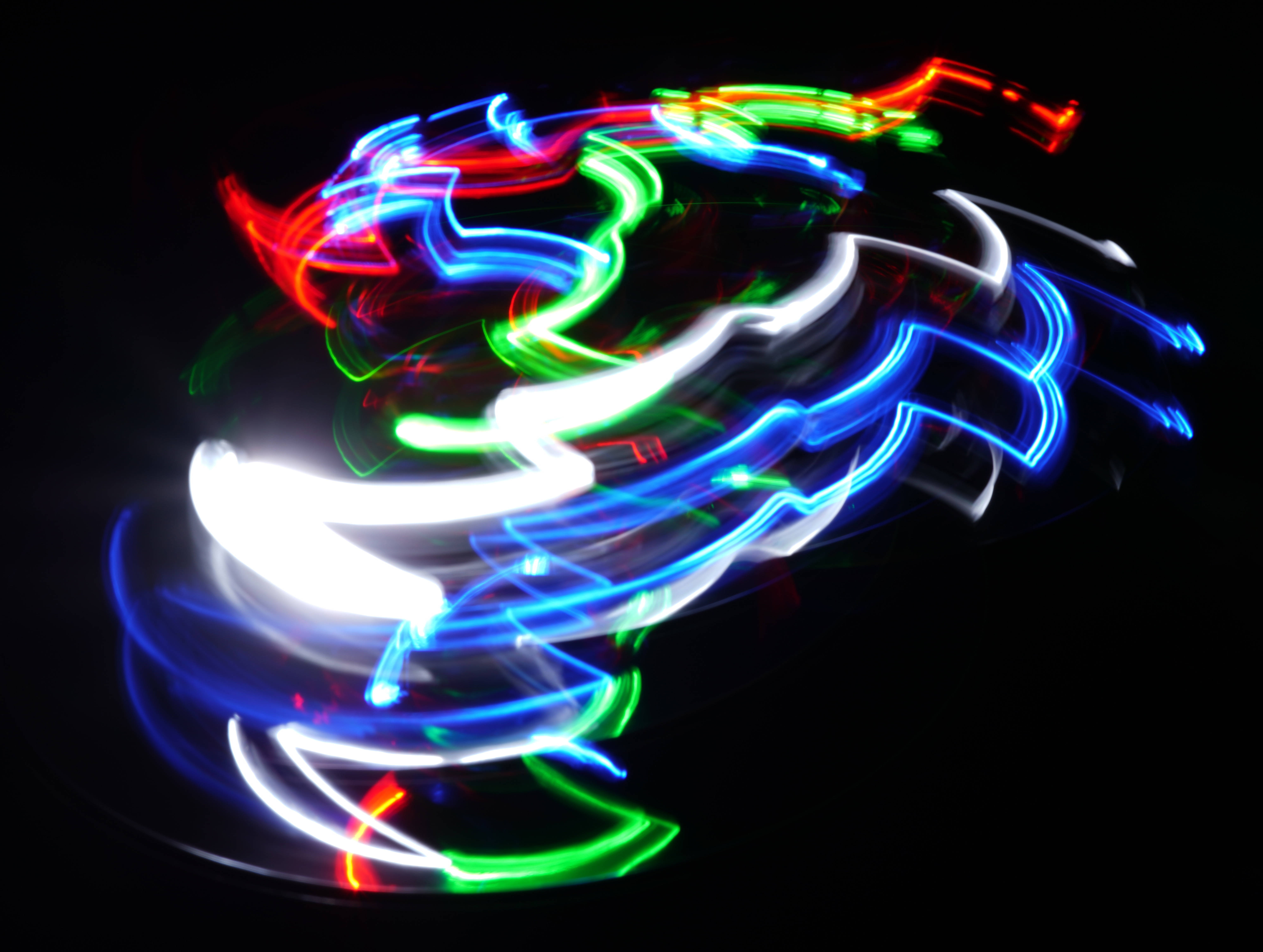 Cyber 桌布 壁紙 — 充滿活力的霓虹燈光軌跡在漆黑的背景上動態旋轉，創造出充滿能量的抽象圖案。