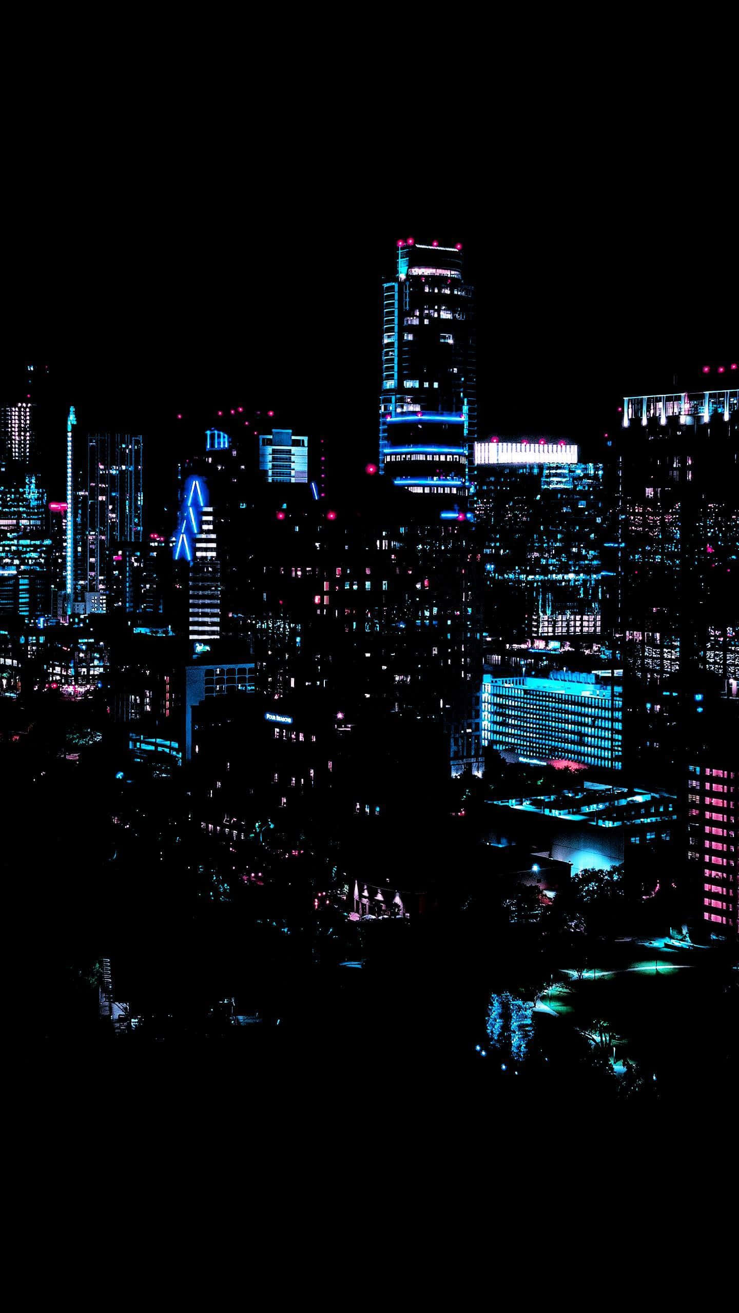 霓虹城市動態圖 桌布 壁紙 — 充滿活力的霓虹燈城市夜景，高聳的摩天大樓在漆黑的天空中閃耀。