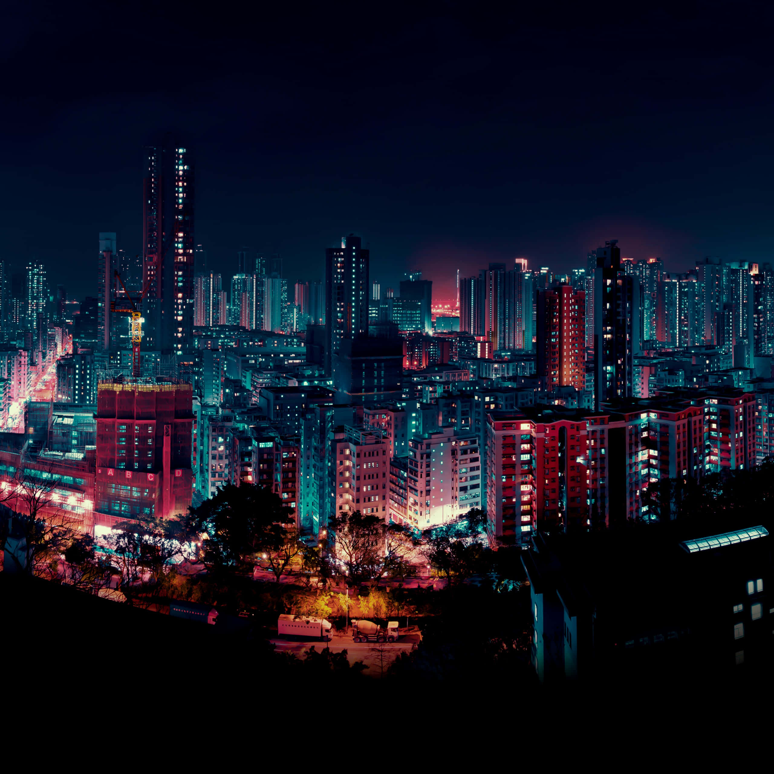 City Lights 桌布 壁紙 — 充滿活力的霓虹燈夜景城市景觀，高聳的摩天大樓在黑暗的天空中閃耀著電光藍和火紅色的光芒。