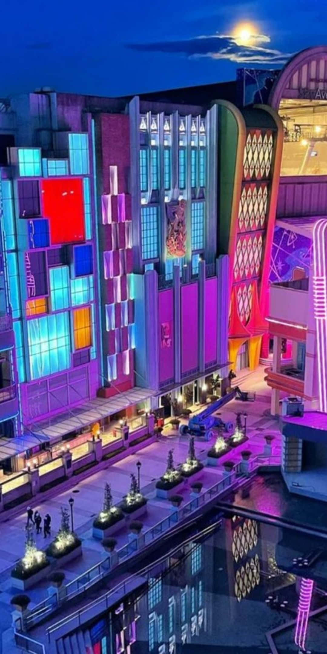 酷 桌布 壁紙 — 充滿活力的霓虹燈建築在月光下的夜空下閃耀，倒映在下方平靜的水道上。