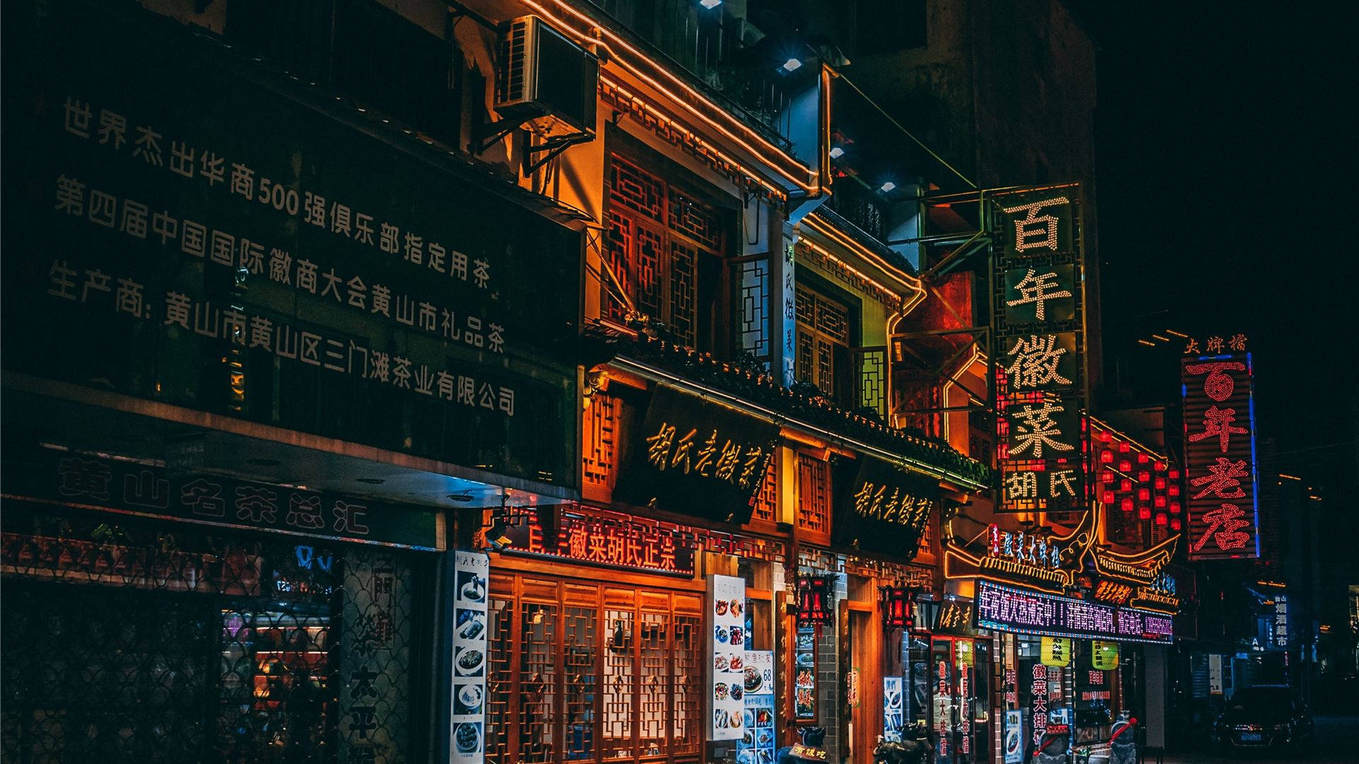 商業 桌布 壁紙 — 充滿活力的霓虹燈招牌照亮了一條繁華的夜市街道，兩旁是傳統中式建築和閃爍的店鋪門面。
