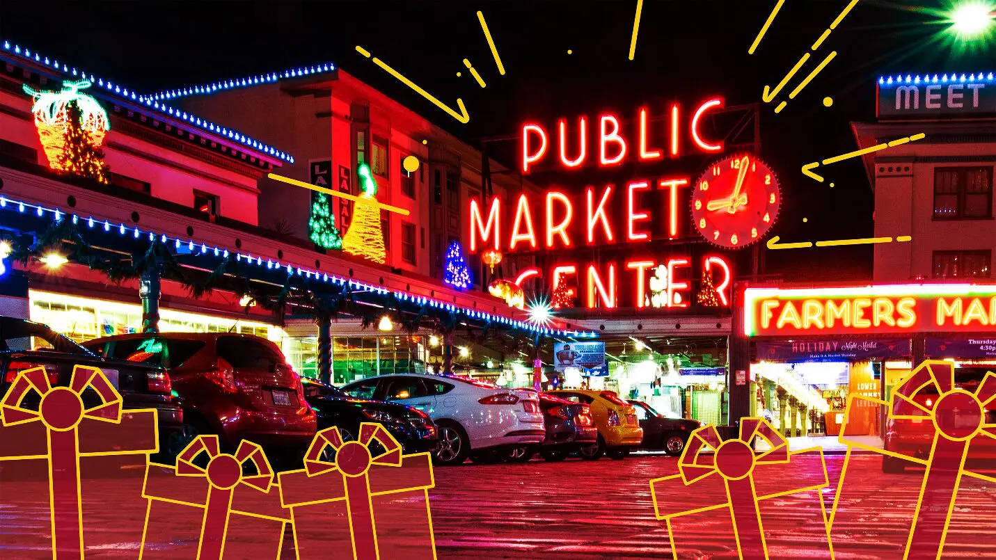 Pike Place Market 桌布 壁紙 — 充滿活力的霓虹燈照亮了公共市場中心繁忙的夜晚場景，包括節日禮物盒輪廓和停放的汽車。